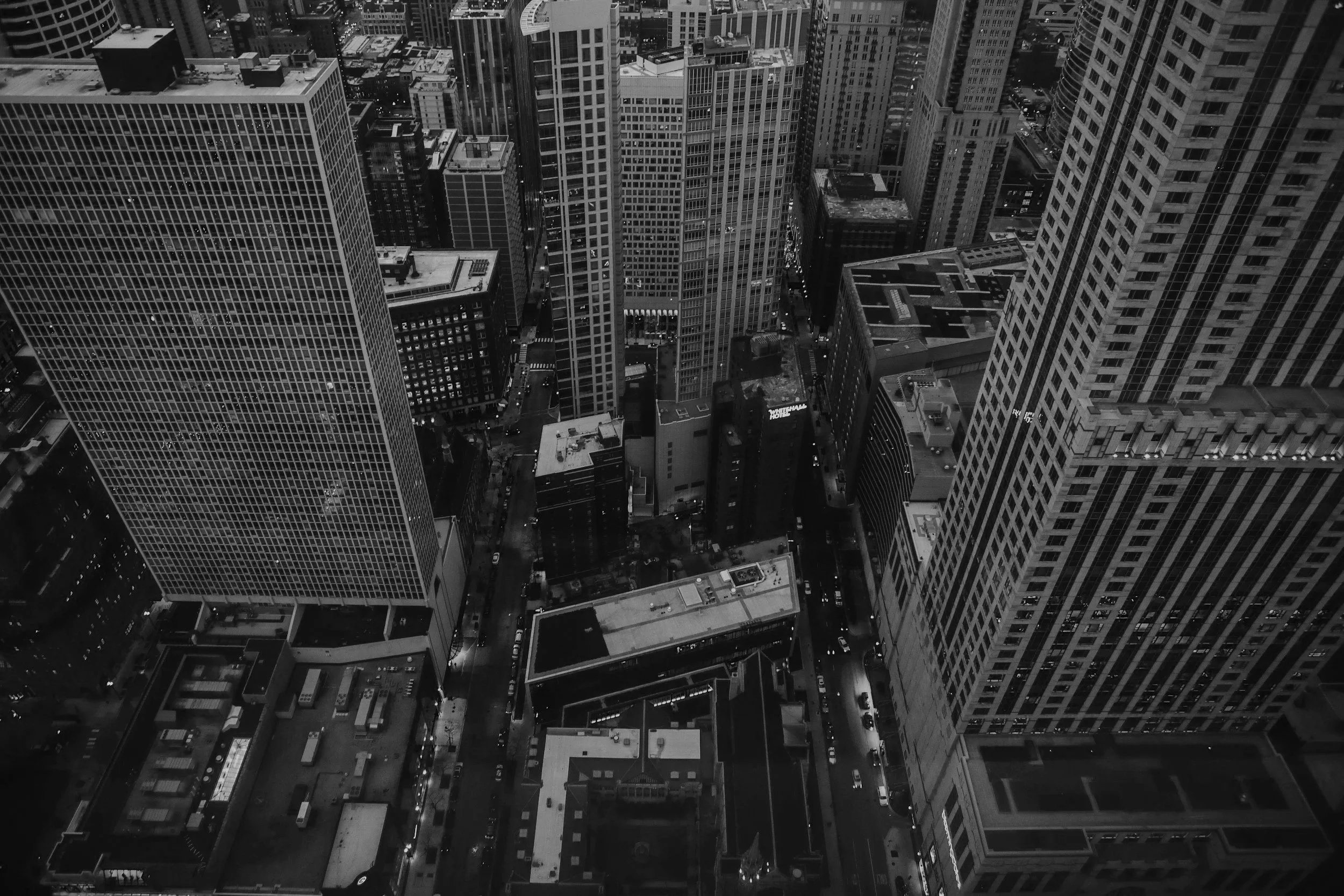 A black and white aerial view of a cityscape with tall skyscrapers and busy streets.