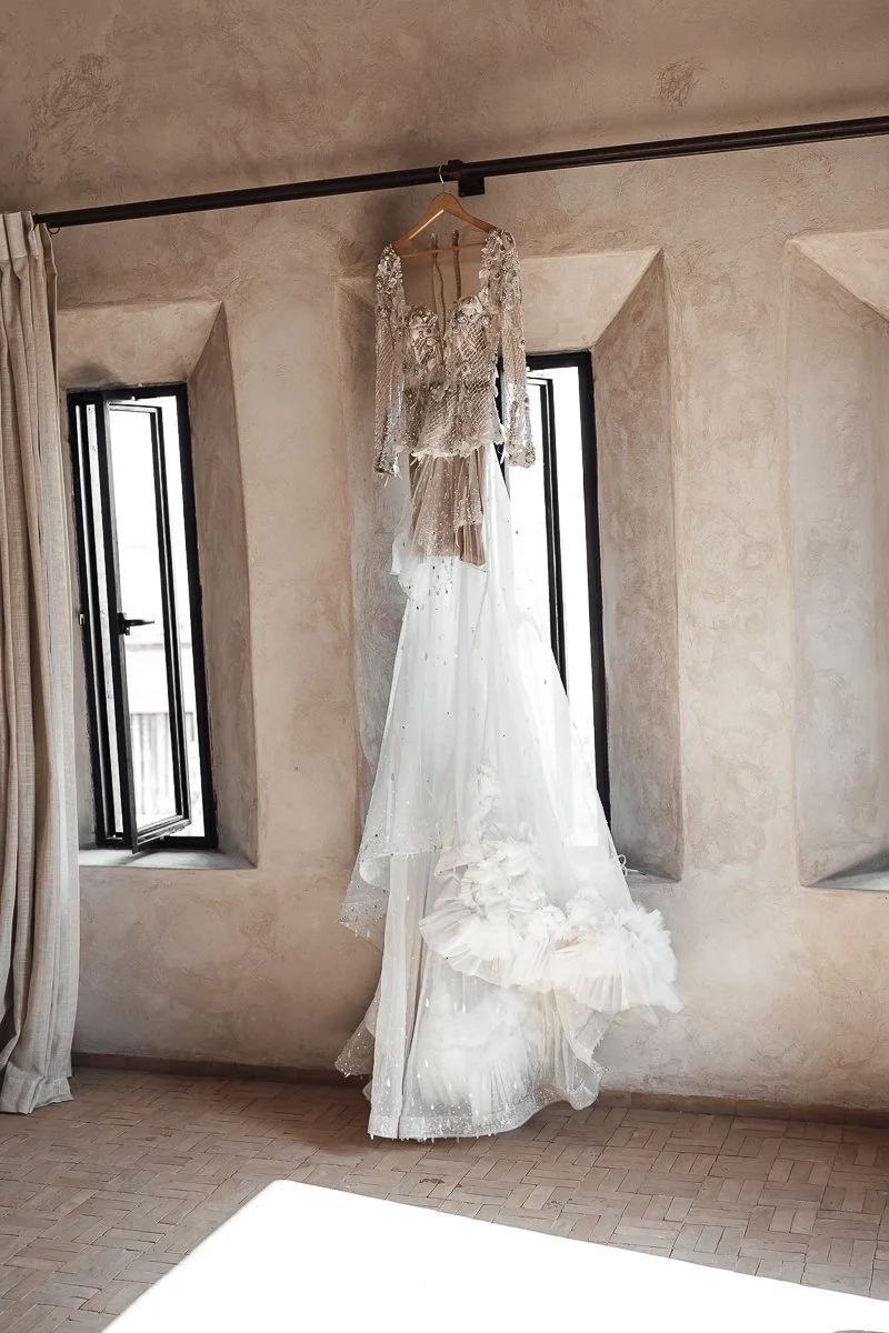 Brautkleid hängt beim Getting Ready zwischen zwei Fenstern