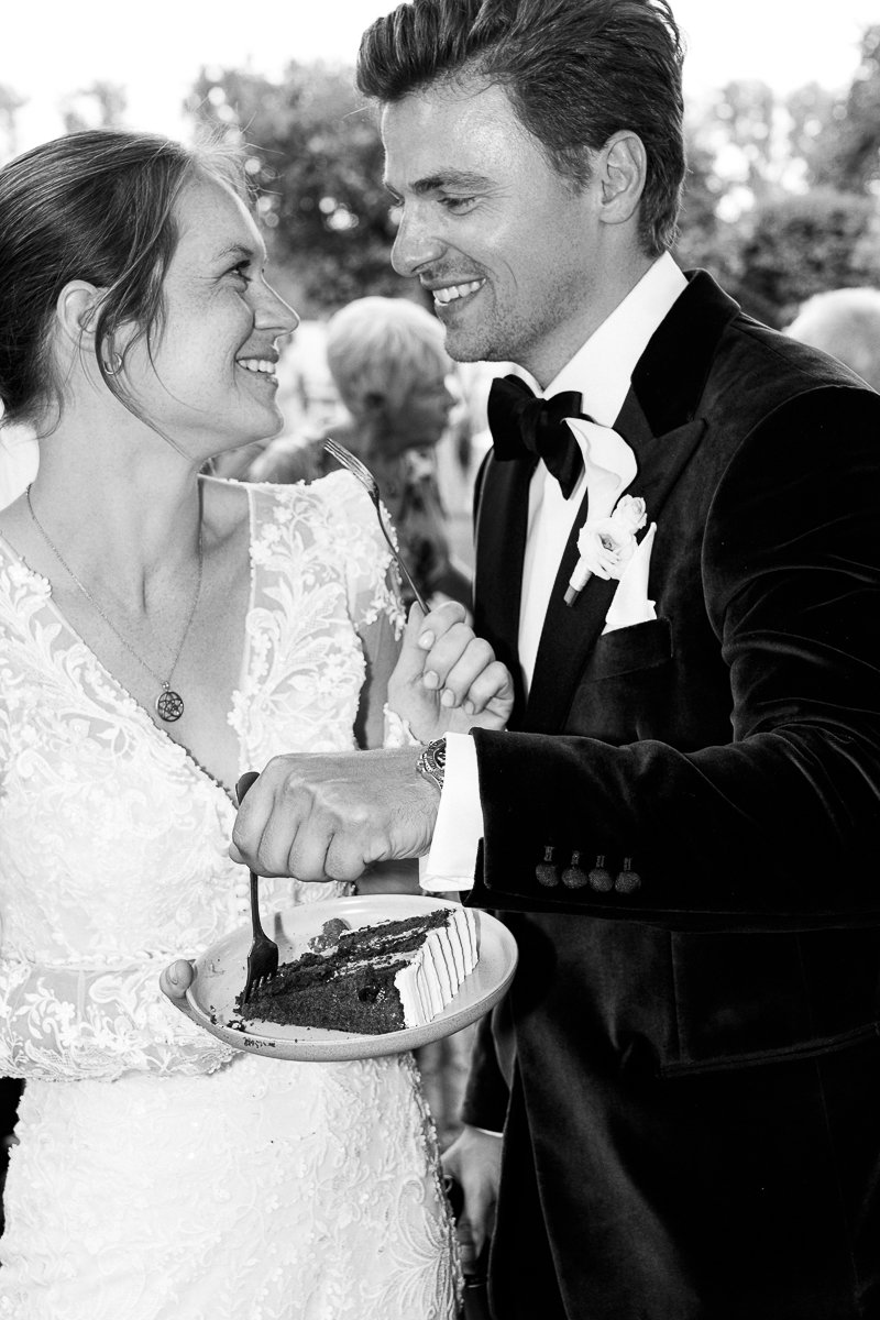 Brautpaar füttert sich gegenseitig mit Hochzeitstorte, schwarz-weiß
