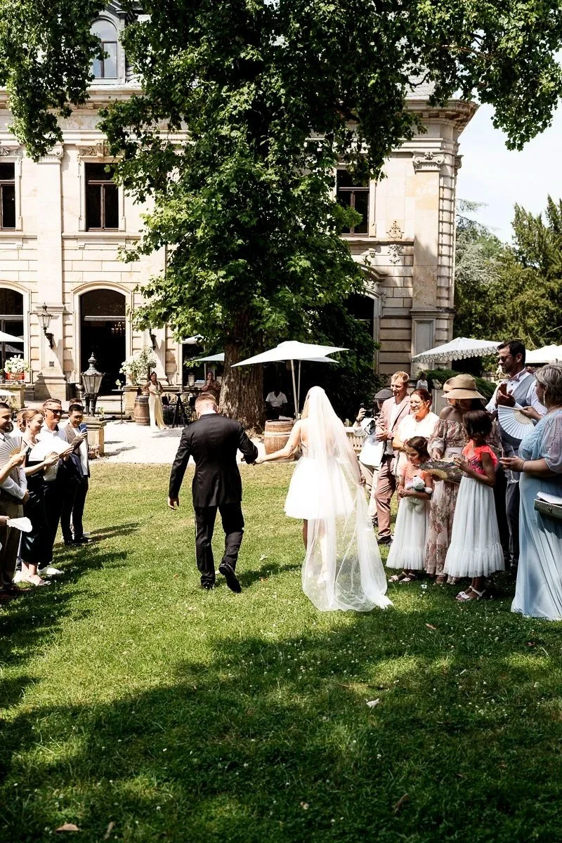 Brautpaar im Garten des Stella Rheni, umgeben von Hochzeitsgästen