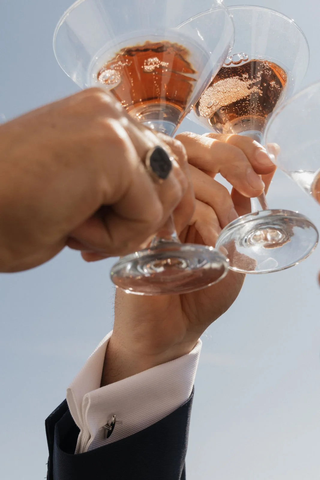 Hochzeitsgäste stoßen mit Champagner vor blauem Himmel an
