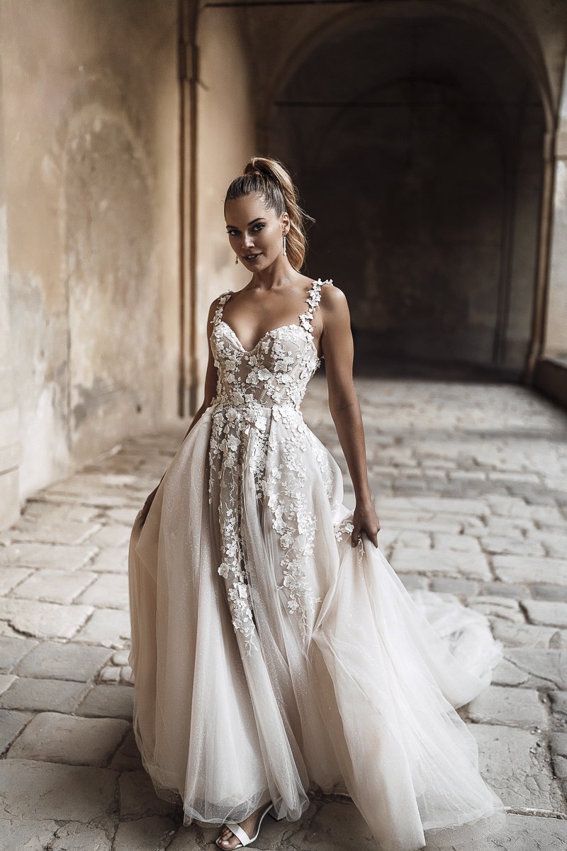Braut im Spitzenkleid mit Blütenapplikationen im Säulengang