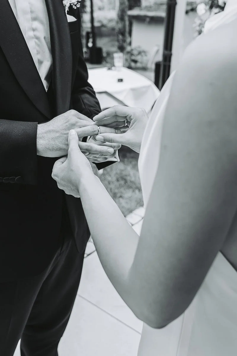 A person holding hands and placing a ring on their partner's finger during a wedding ceremony.