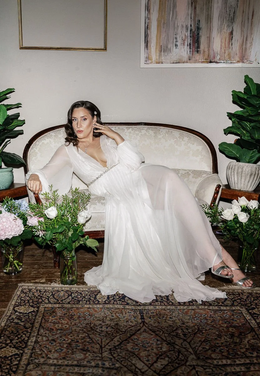 Braut auf einem Vintage-Sofa zwischen Blumen im LA DÜ Düsseldorf