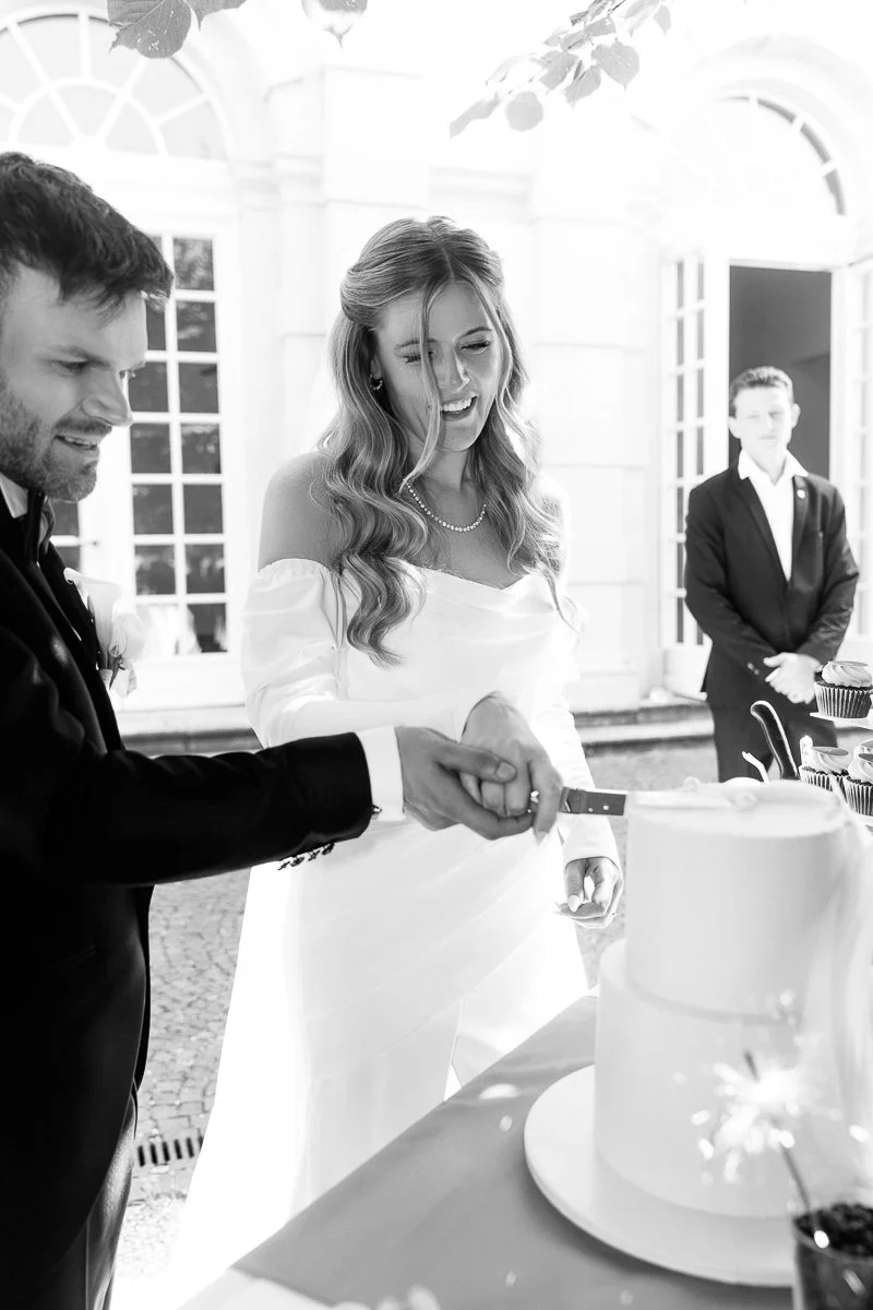 Brautpaar schneidet die Hochzeitstorte an, schwarz-weiß