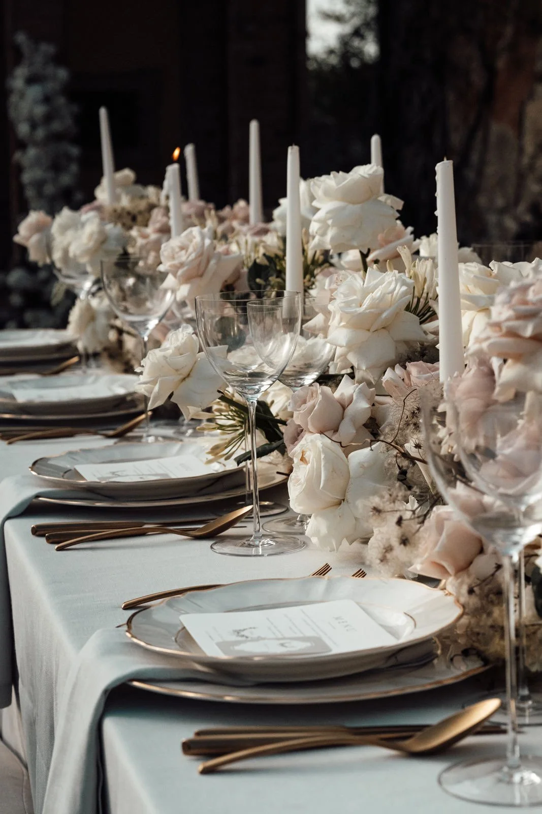 Hochzeitstafel mit Rosen, Kerzen und goldenem Besteck