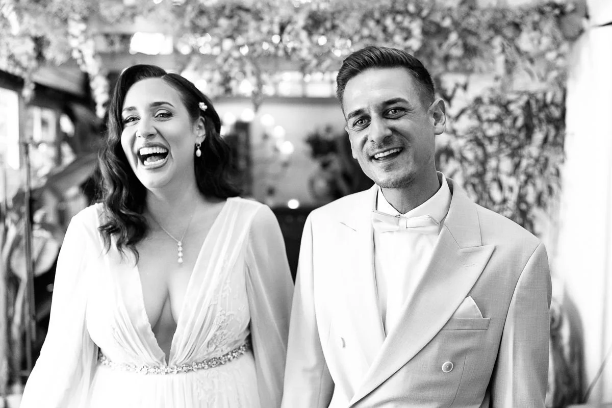 Schwarzweißes Bild: Kate und Marco lachen während der Trauung