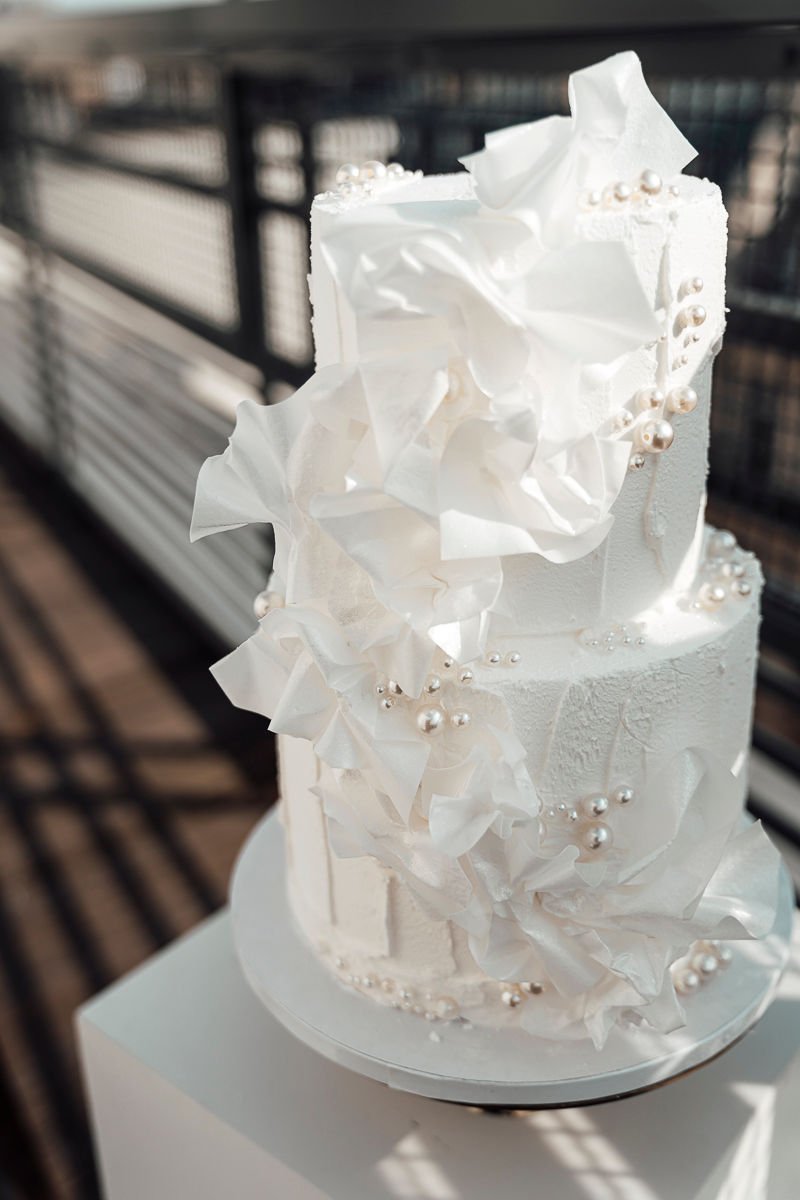 Weiße Hochzeitstorte mit Papier-Rüschen und Perlen