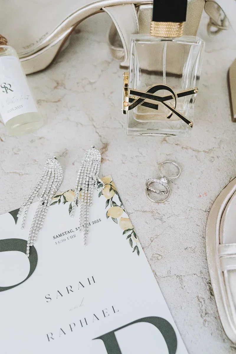 Hochzeitseinladung mit Schmuck, Parfum und Brautschuhen auf Marmor – Detailaufnahme