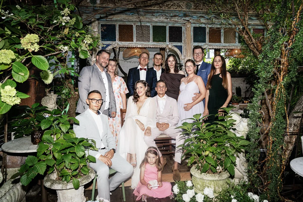 Familienfoto mit Brautpaar vor der grünen Kulisse des Innenhofs