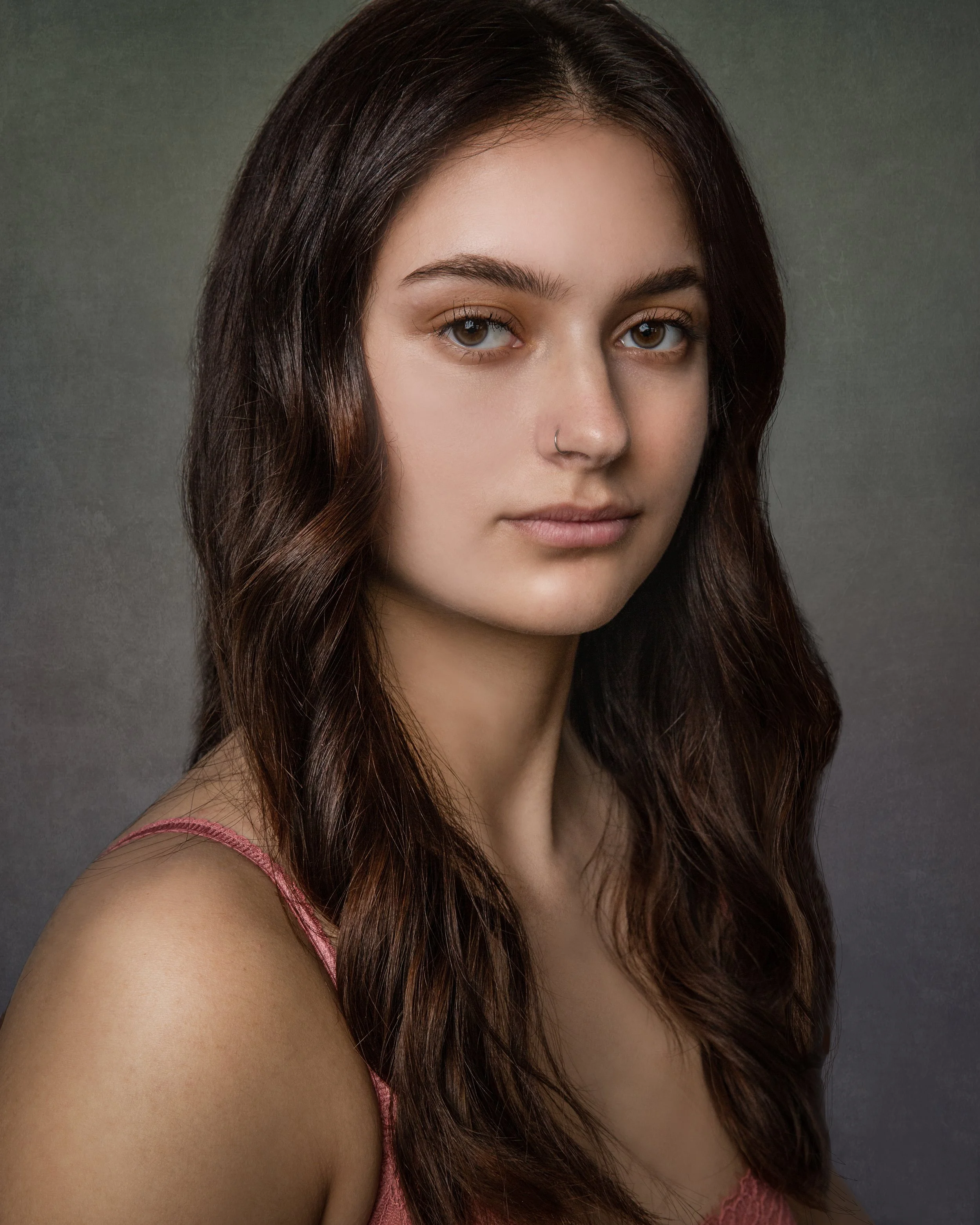 Studio portrait of a young woman looking toward the camera during a senior portrait session.