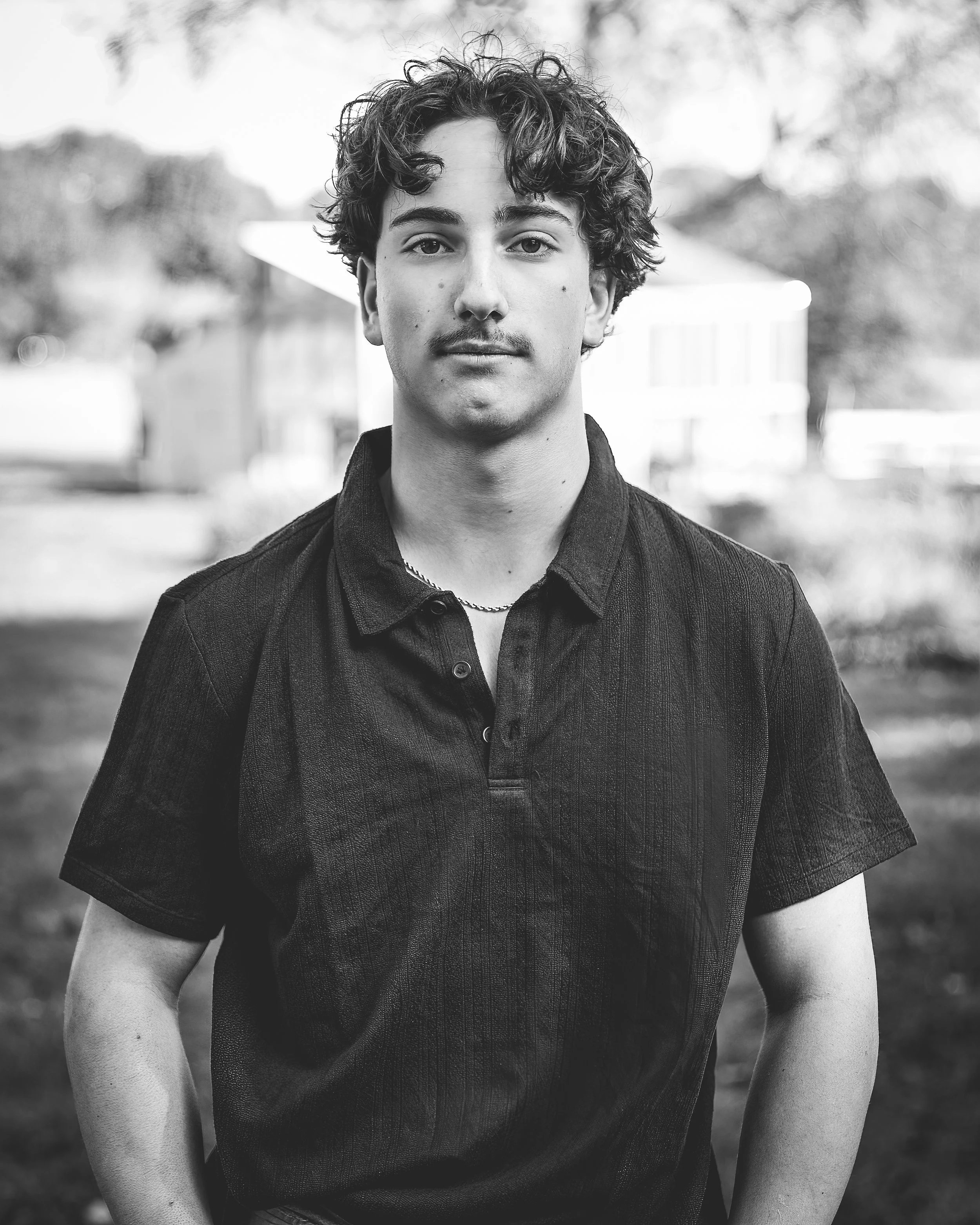 Black-and-white senior portrait of a young man outdoors at Spencer Pierce Farm in Newbury, MA