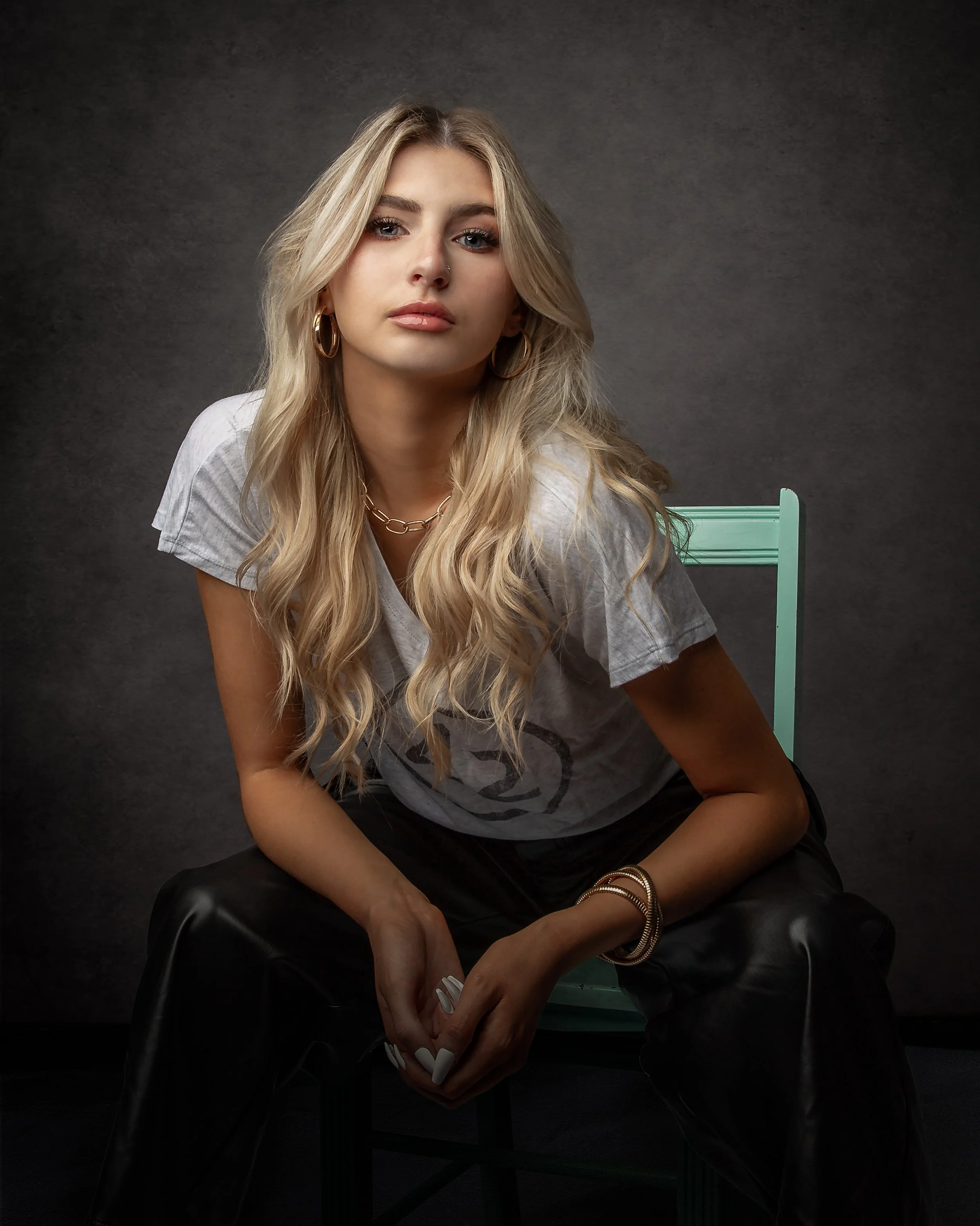 Studio senior portrait of a young woman seated and looking toward the camera.