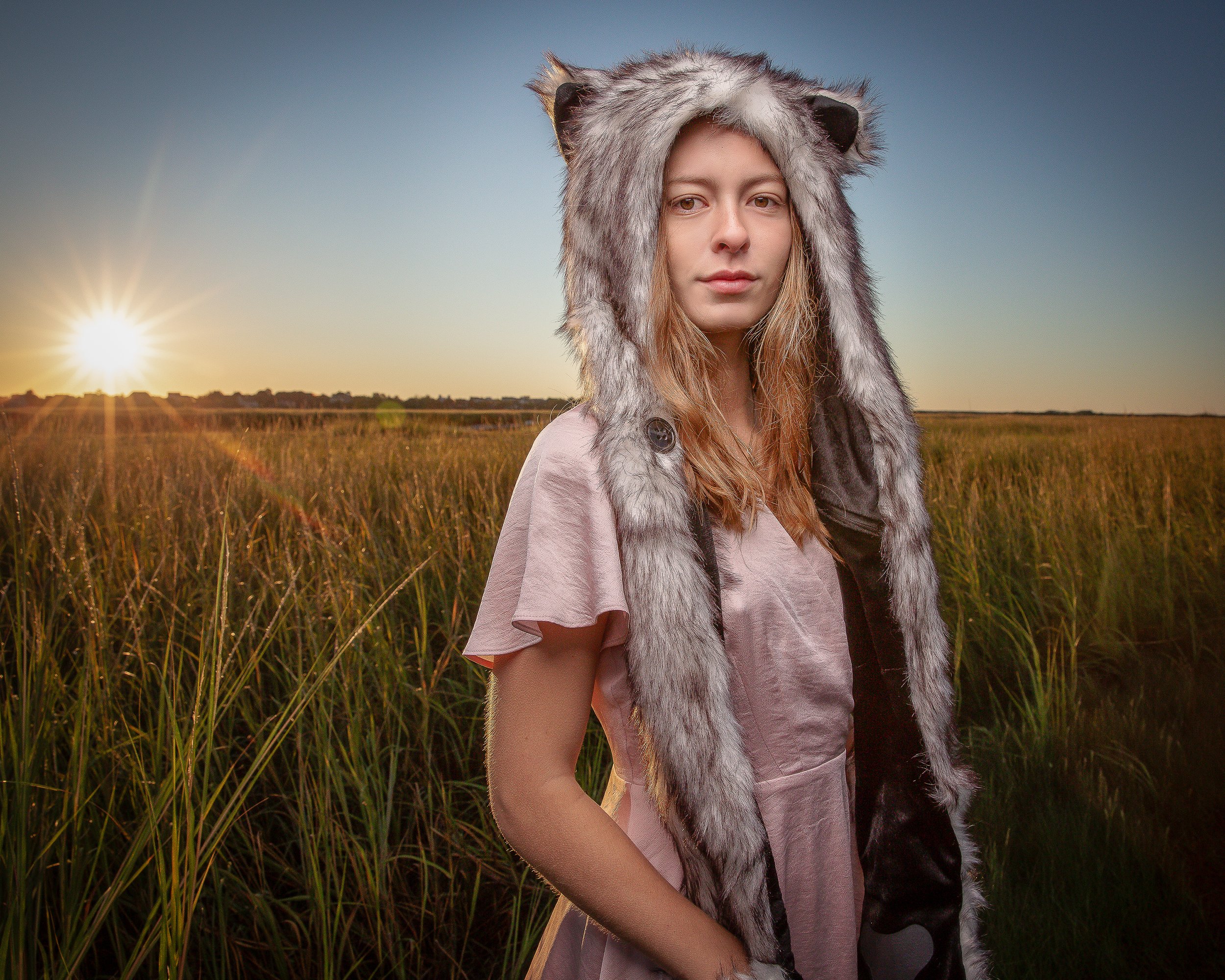 Young woman wearing a wolf hat during an outdoor senior portrait session at sunrise