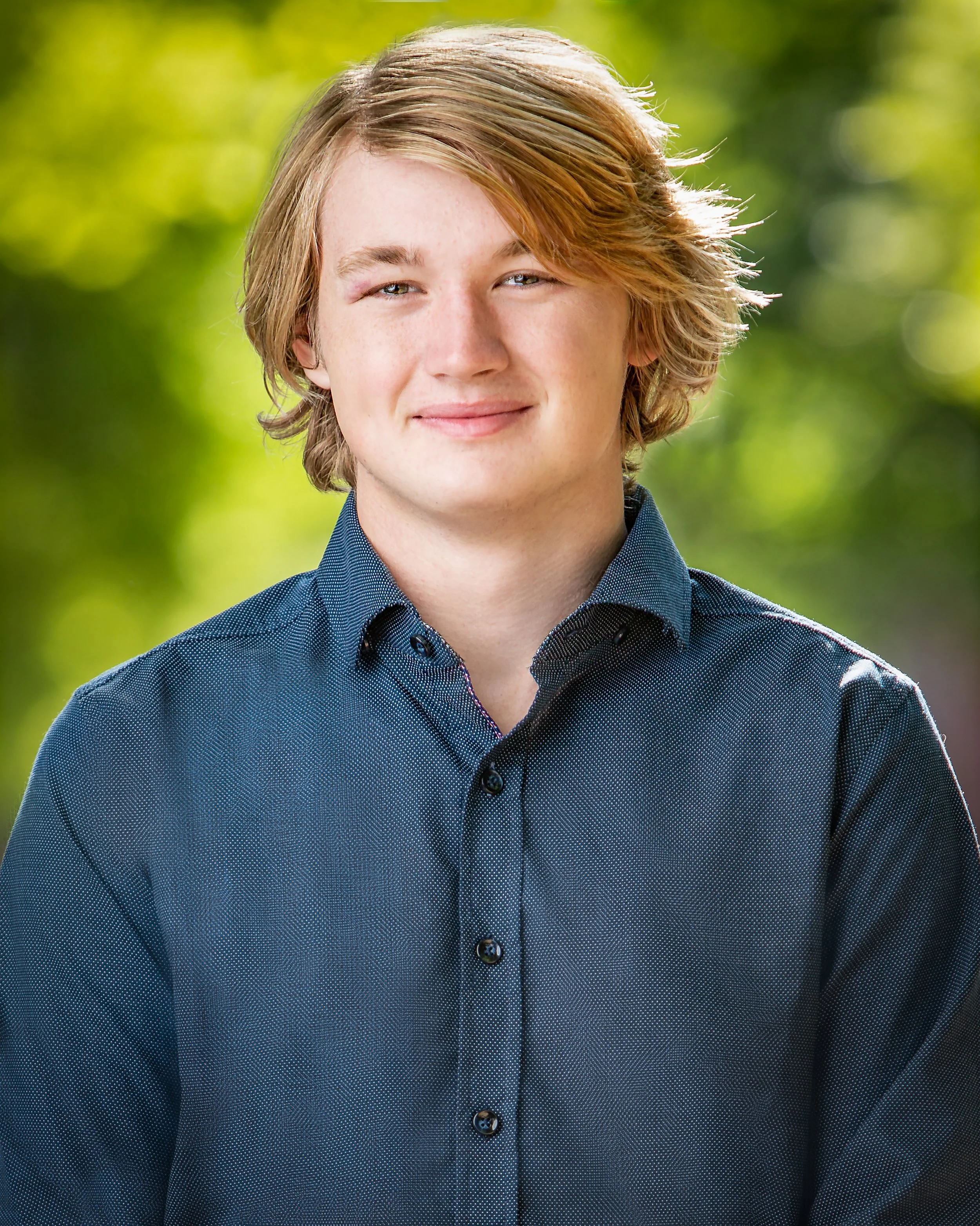 High school senior portrait with natural outdoor lighting and a soft green background in downtown Newburyport.