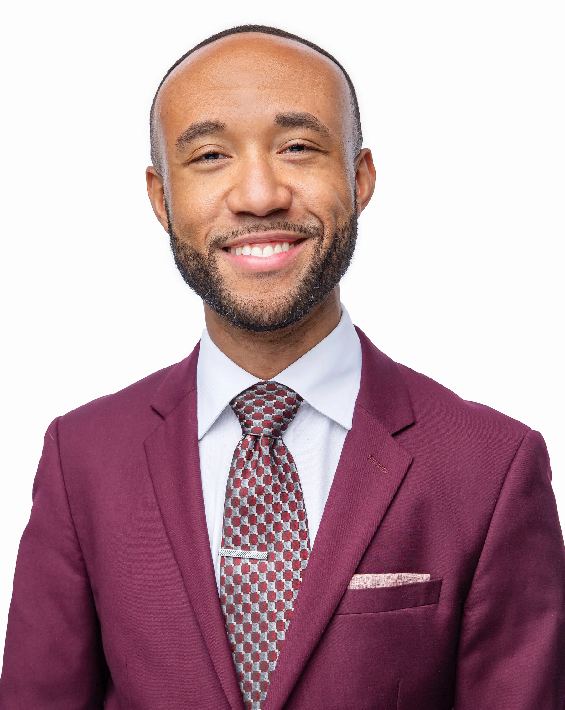 Executive headshot of the Chief of Staff at Cellino Biotech wearing a burgundy suit jacket, patterned tie, and white dress shirt. He smiles confidently against a clean white background.