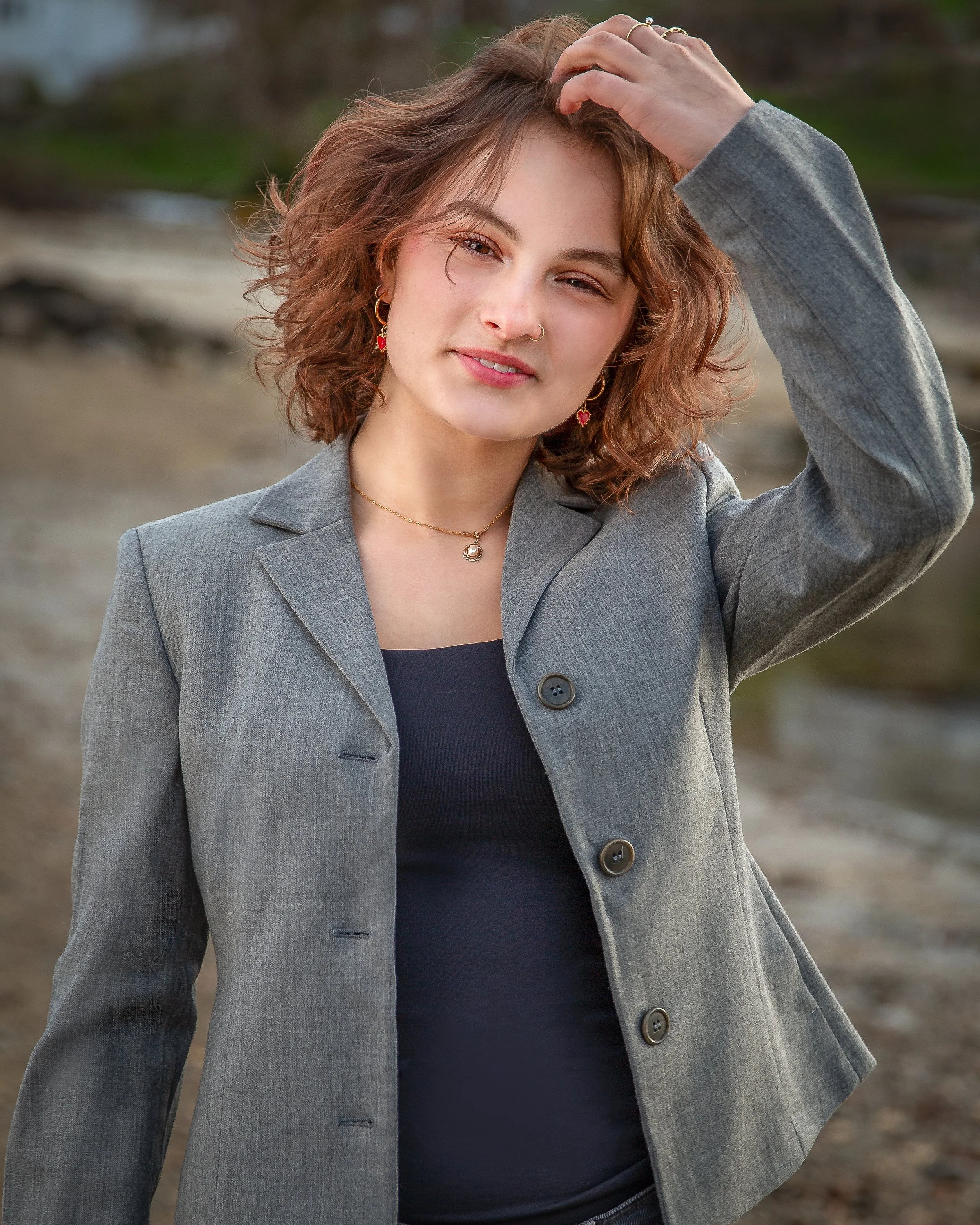 Senior portrait of a high school student in a gray blazer photographed along the New England shoreline in Gloucester, MA