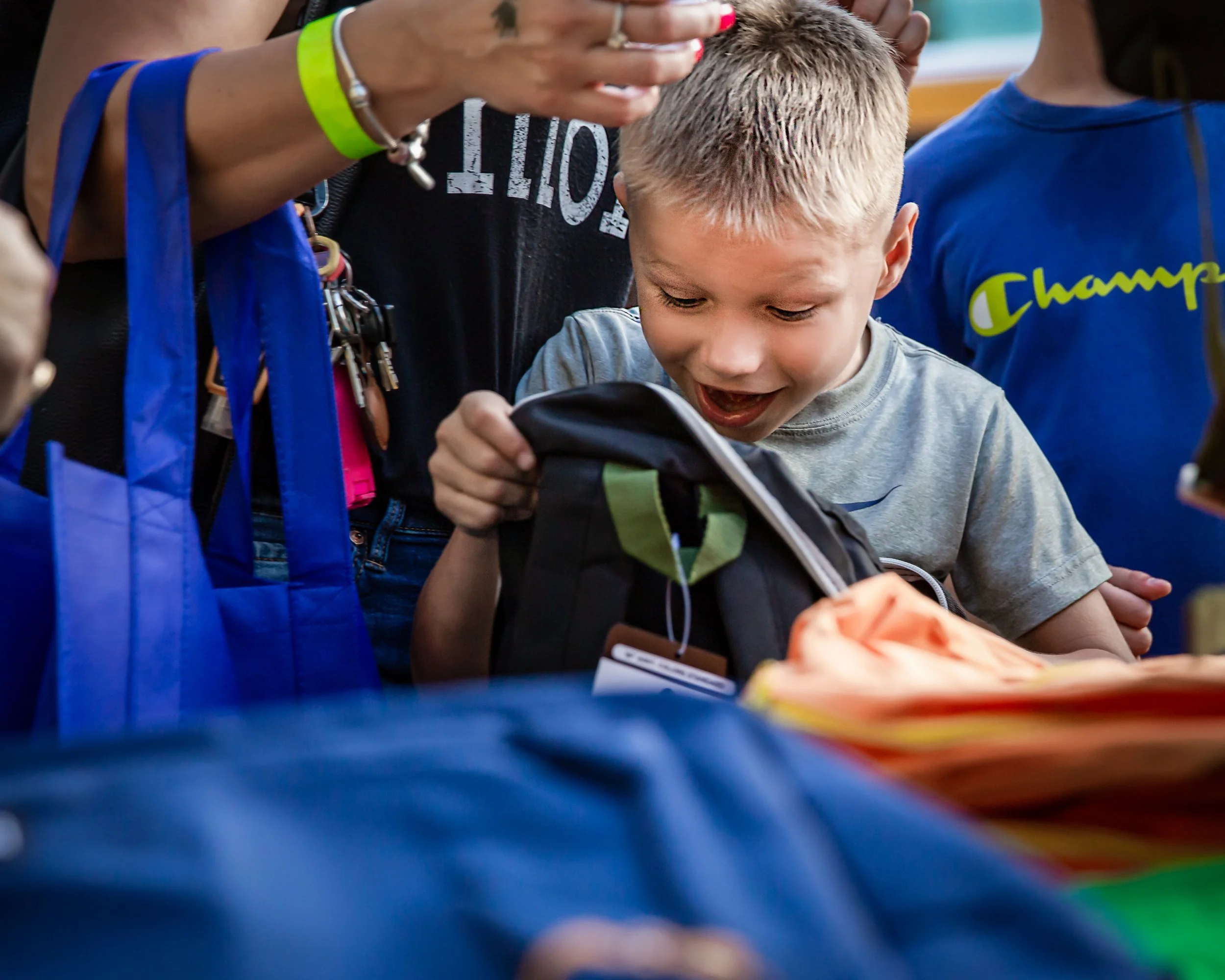 Child excitedly opens a new backpack filled with school supplies during a Welcome to Kindergarten community event at Boston's Children's Museum.
