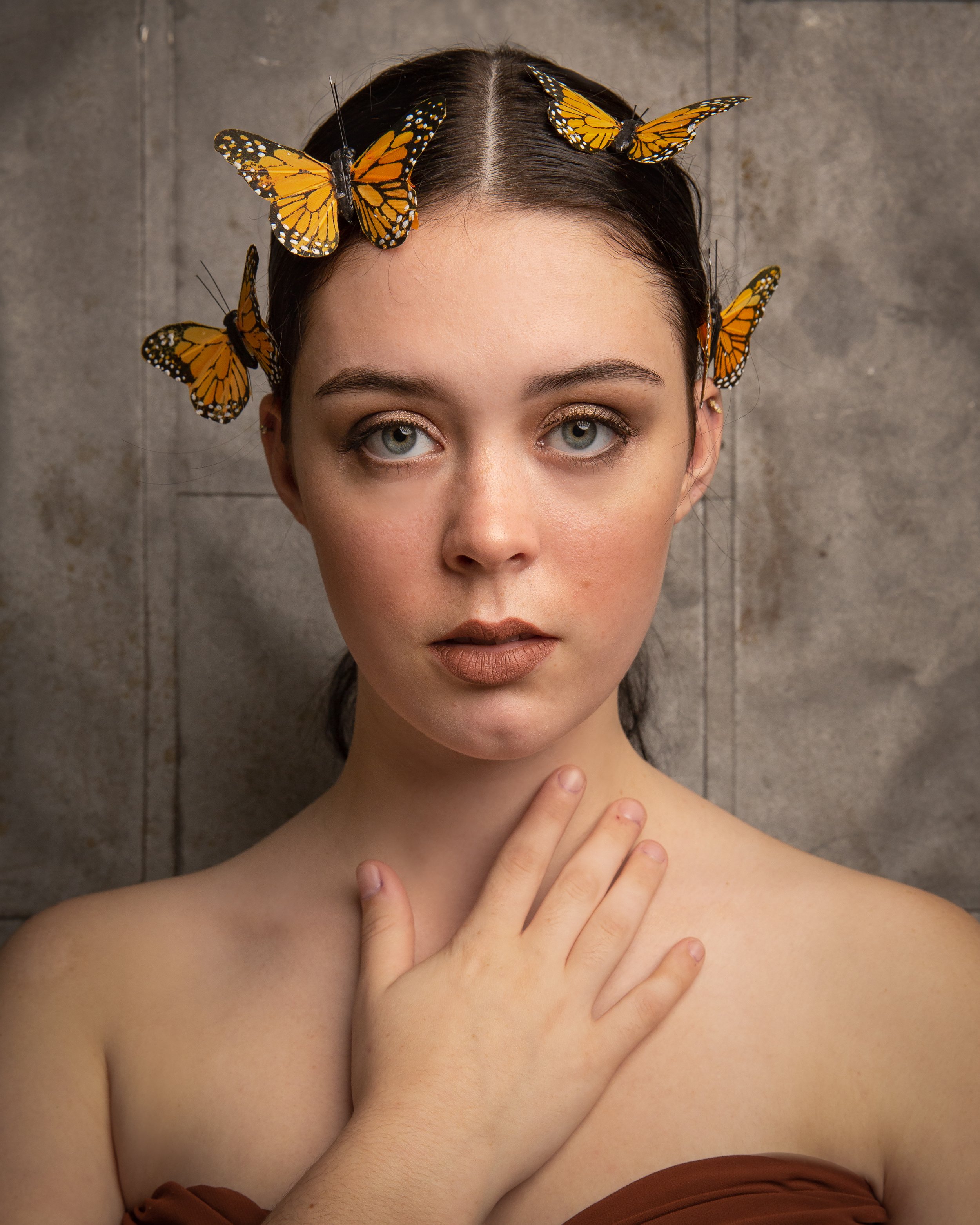 Creative senior portrait of a young woman with monarch butterflies in her hair.