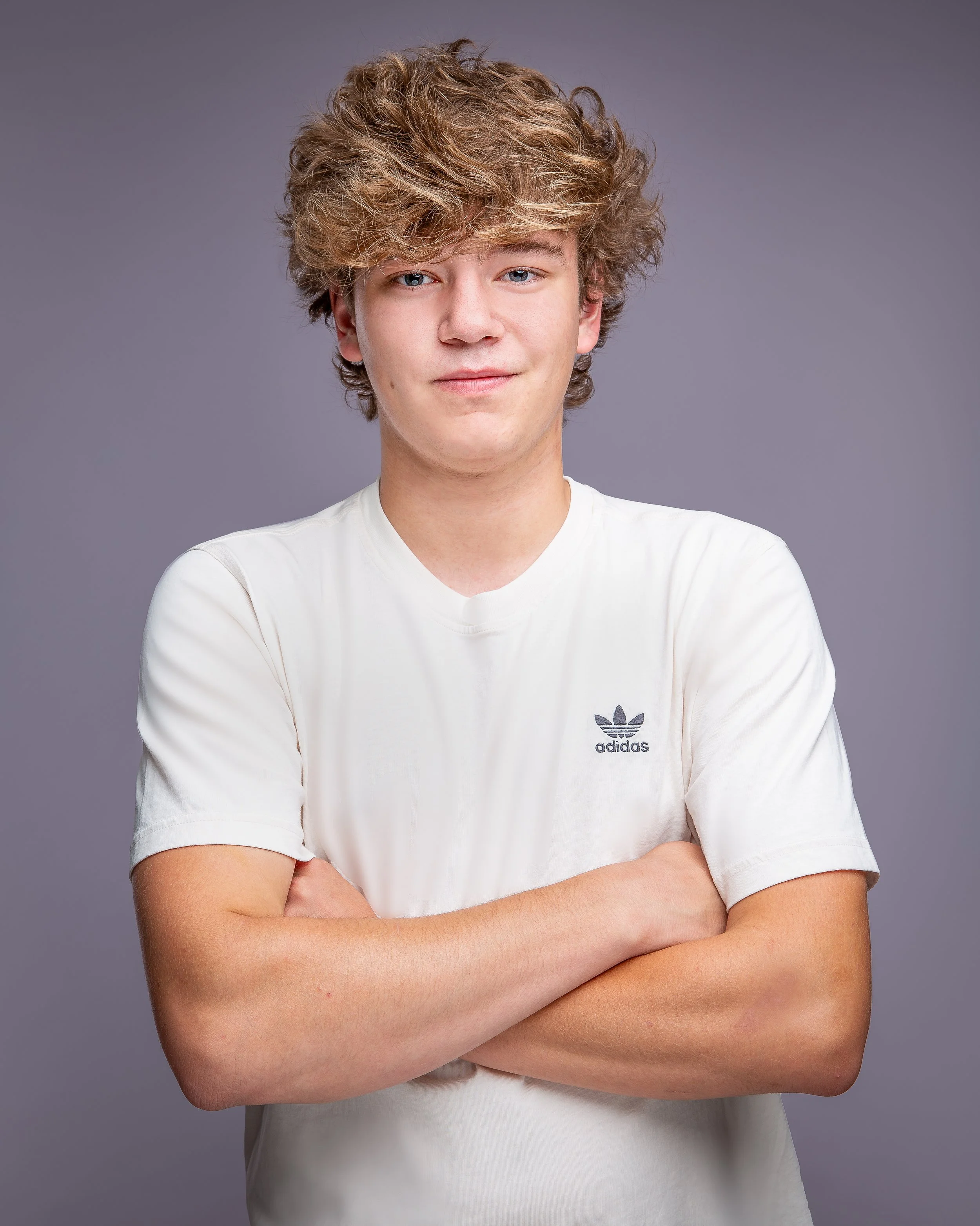Studio senior portrait of a young man with his arms crossed.