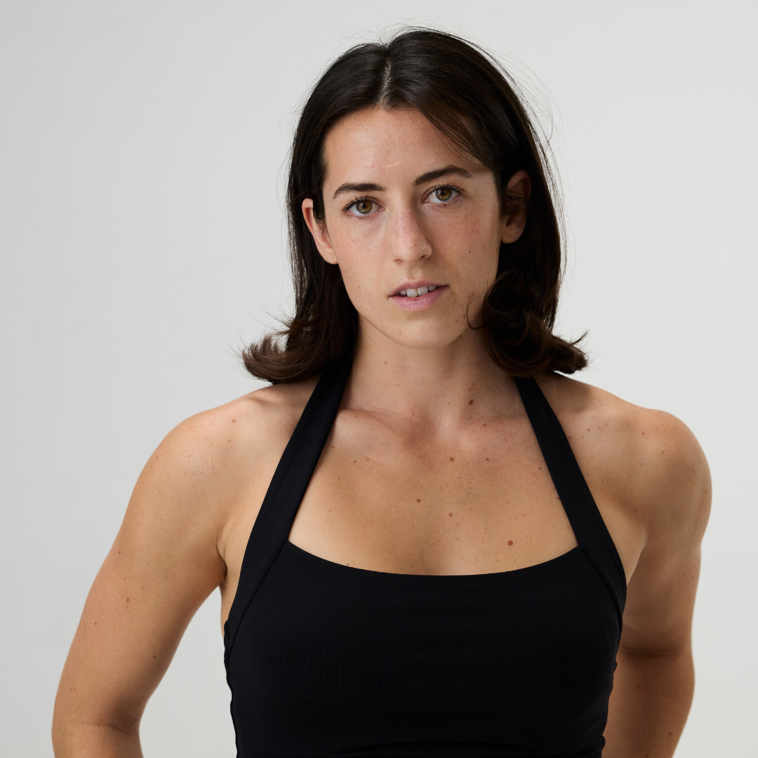 A young woman with dark brown hair wearing a black sports tank top against a plain white background.