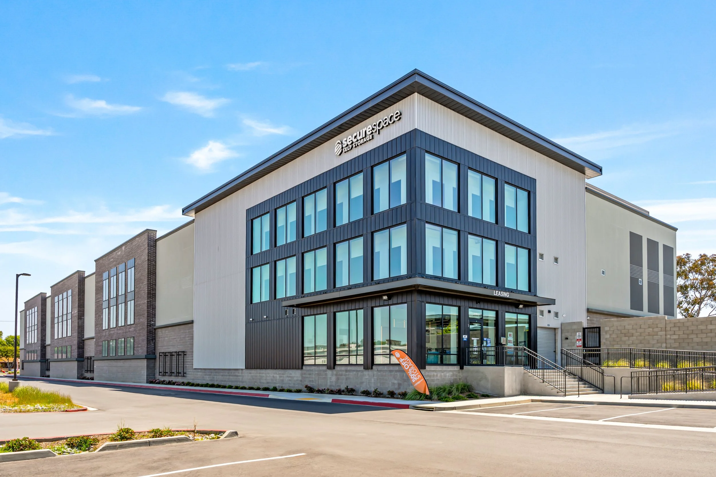 Modern commercial building with large windows, signage reading 'surespace', and a parking lot in front.