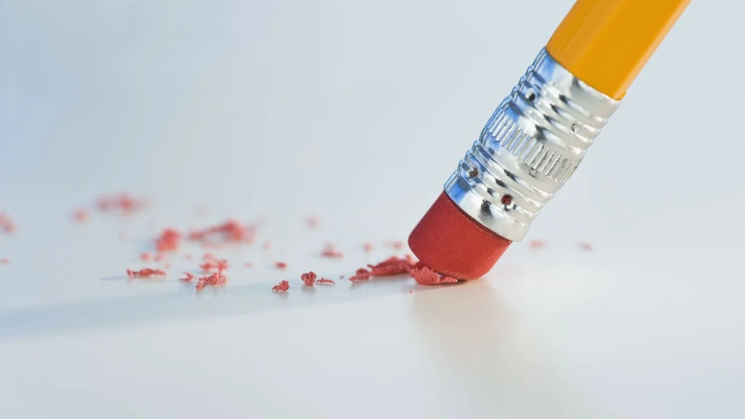 A pencil eraser removing graphite marks from a surface, illustrating the act of removing work.