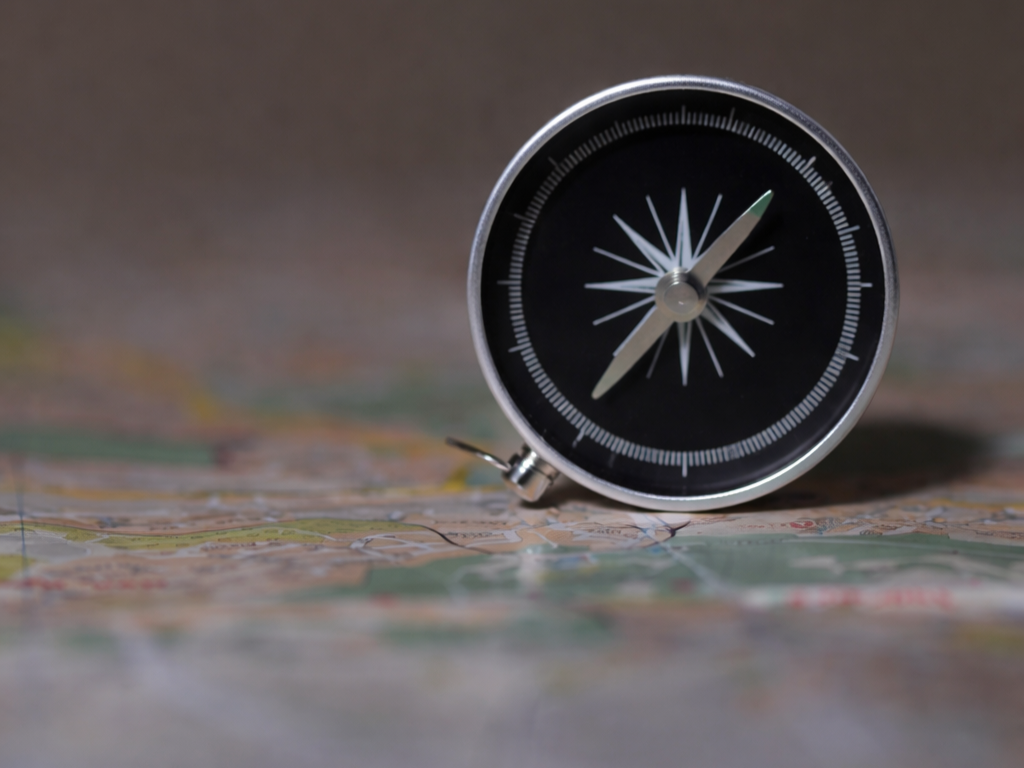 A compass resting on an unfolded map, illustrating the need for clear direction before holding teams accountable.