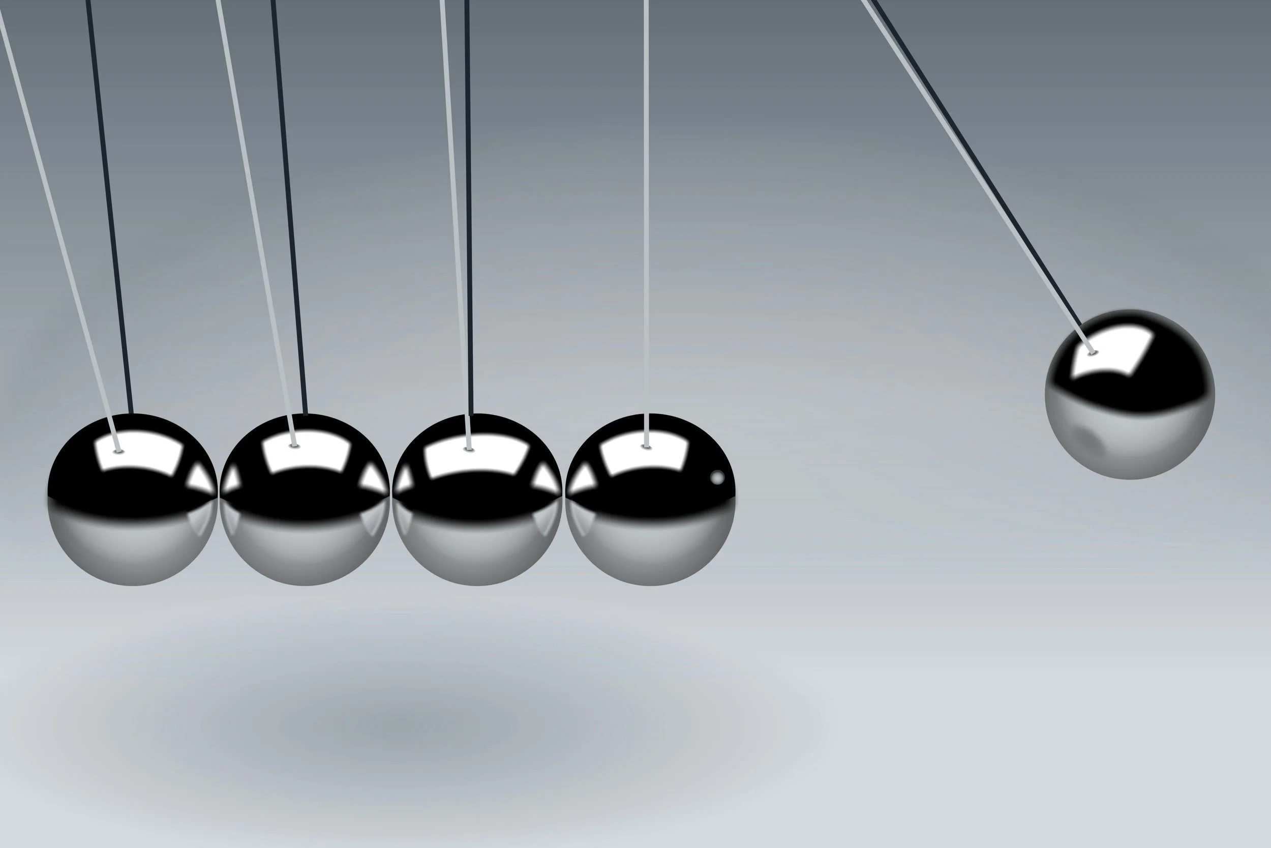 A close-up of a Newton’s cradle in motion, illustrating activity without forward progress.