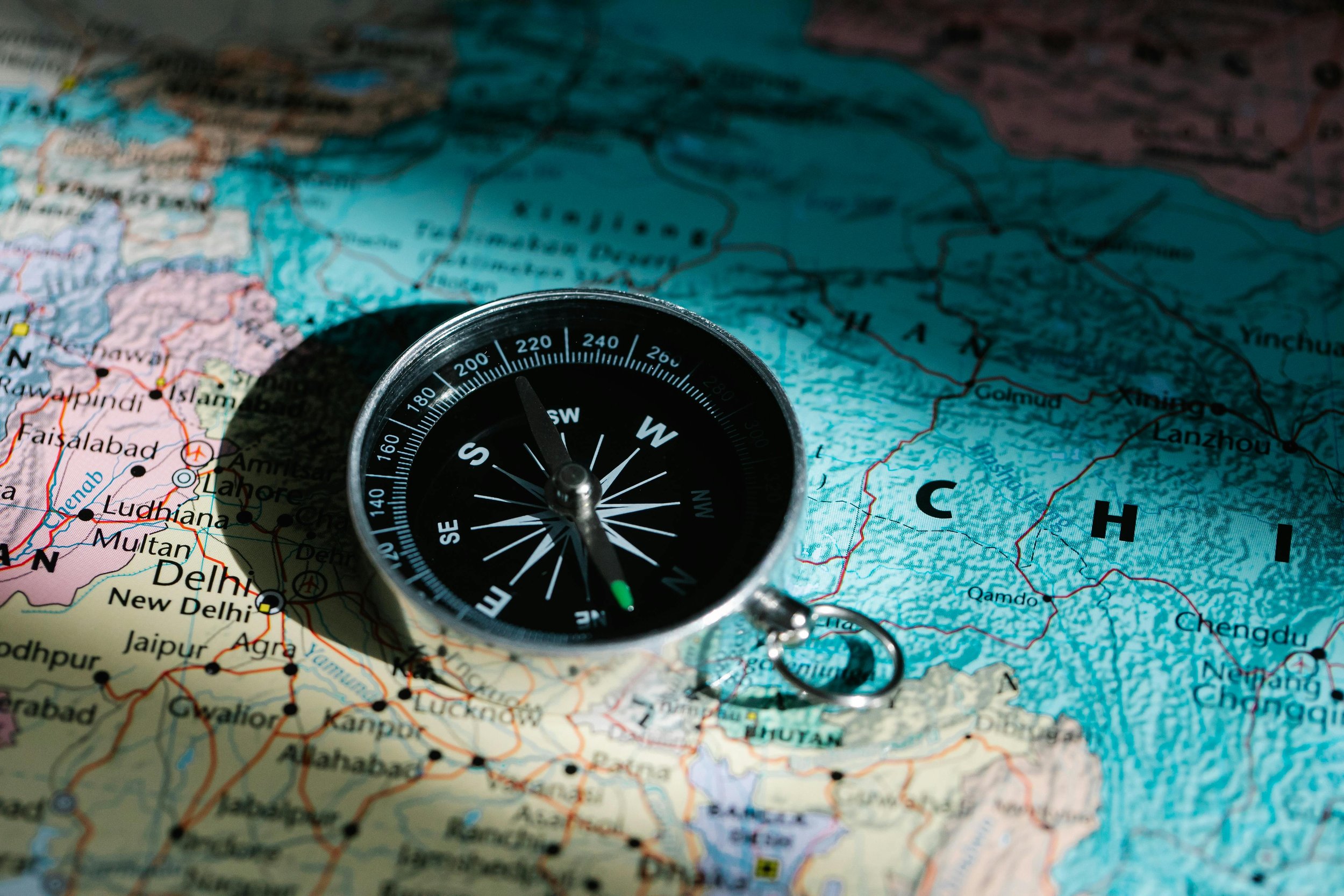 A silver compass resting on a detailed map, symbolizing strategic direction and roadmap alignment for product teams.