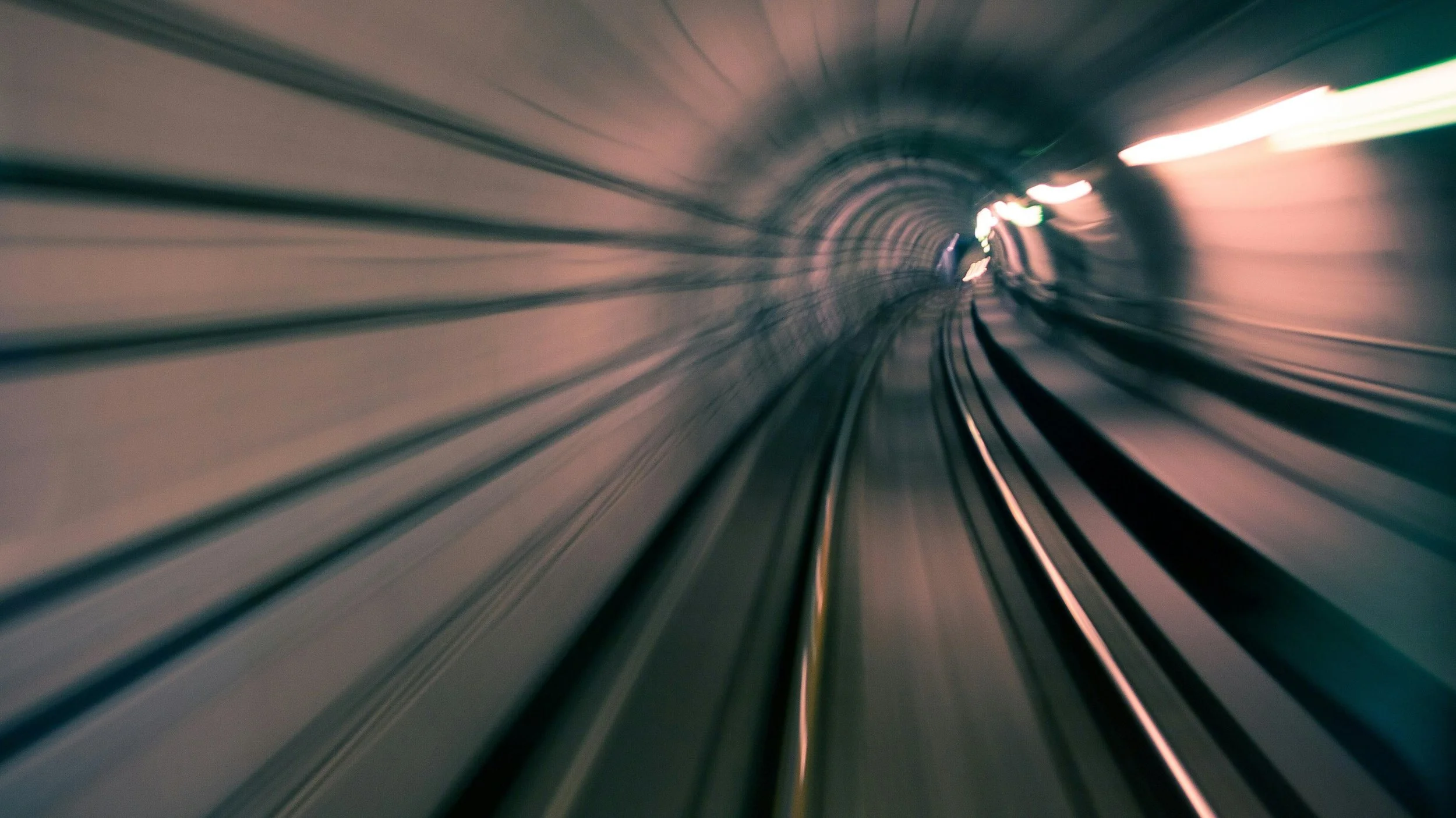 A subway train captured in motion blur speeding through a tunnel, conveying rapid movement and forward momentum.
