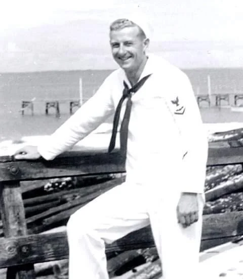 Black-and-white photo of a sailor in uniform by the water, representing the nautical inspiration behind Navis Product Partners.
