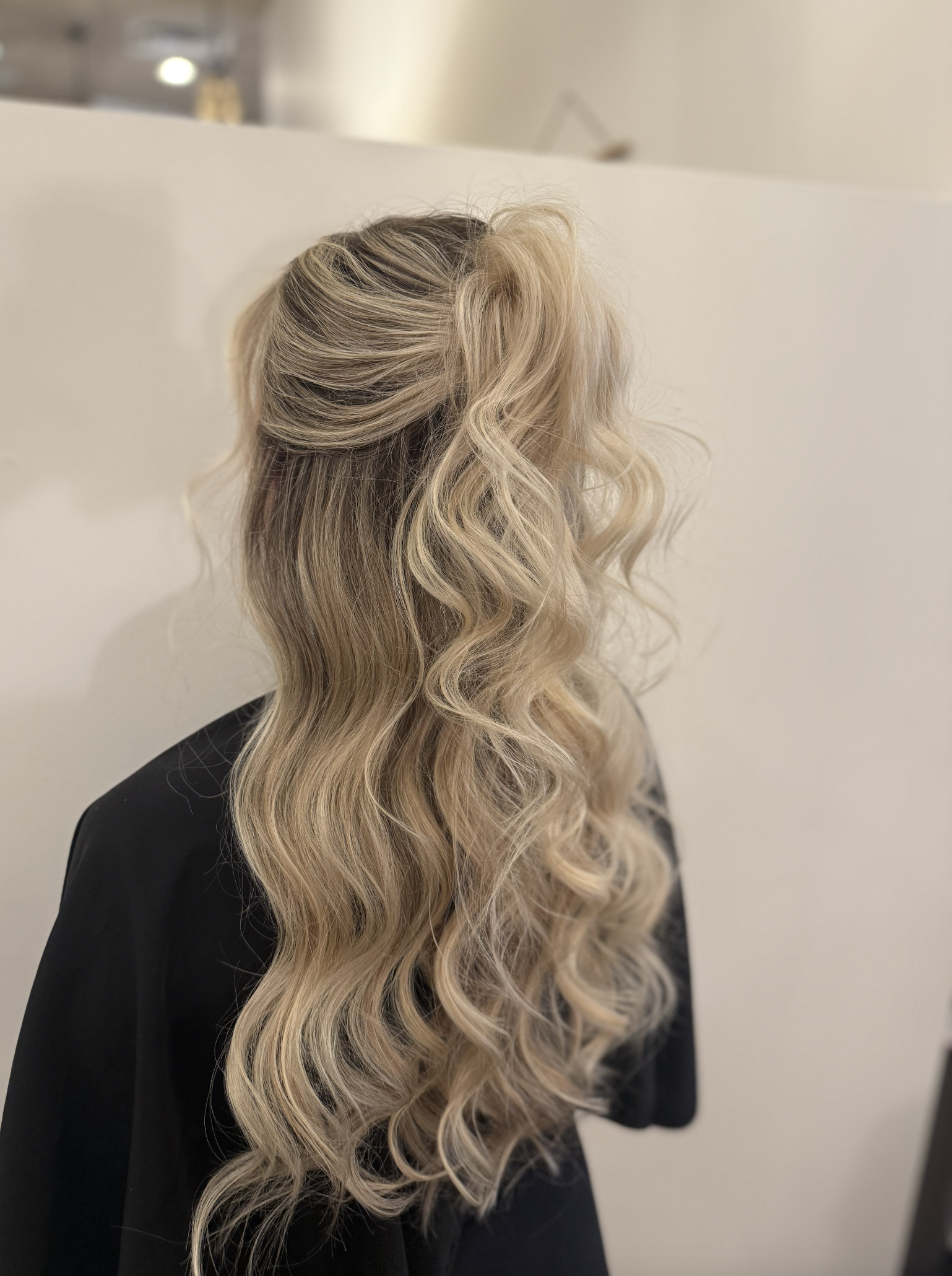 Blonde woman with long, wavy hair facing away from the camera.