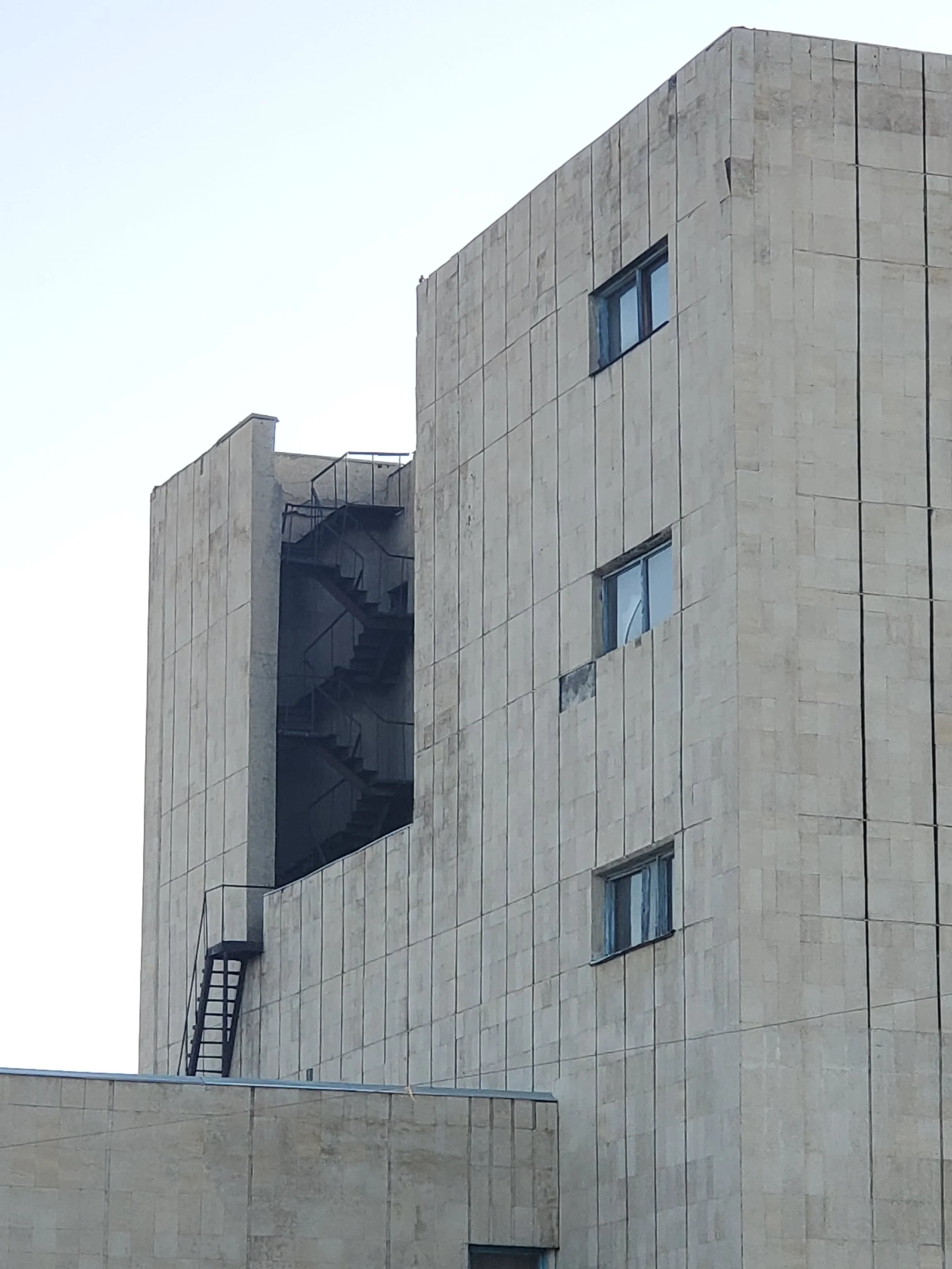 A modern, multi-storey building with a staircase on the outside, visible through an open window on the side.