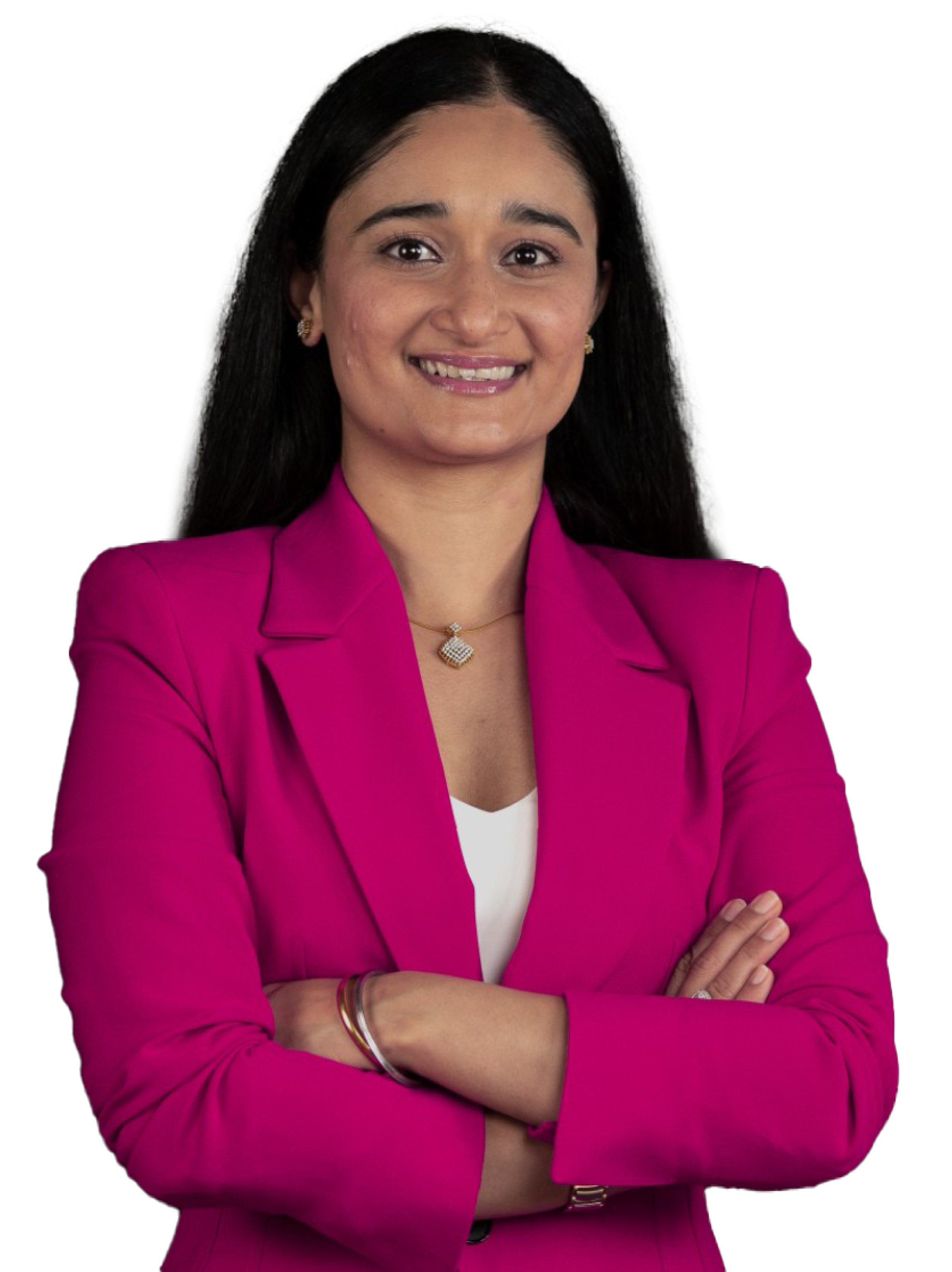 A woman with long dark hair wearing a pink blazer, white top, gold jewelry, smiling with arms crossed.