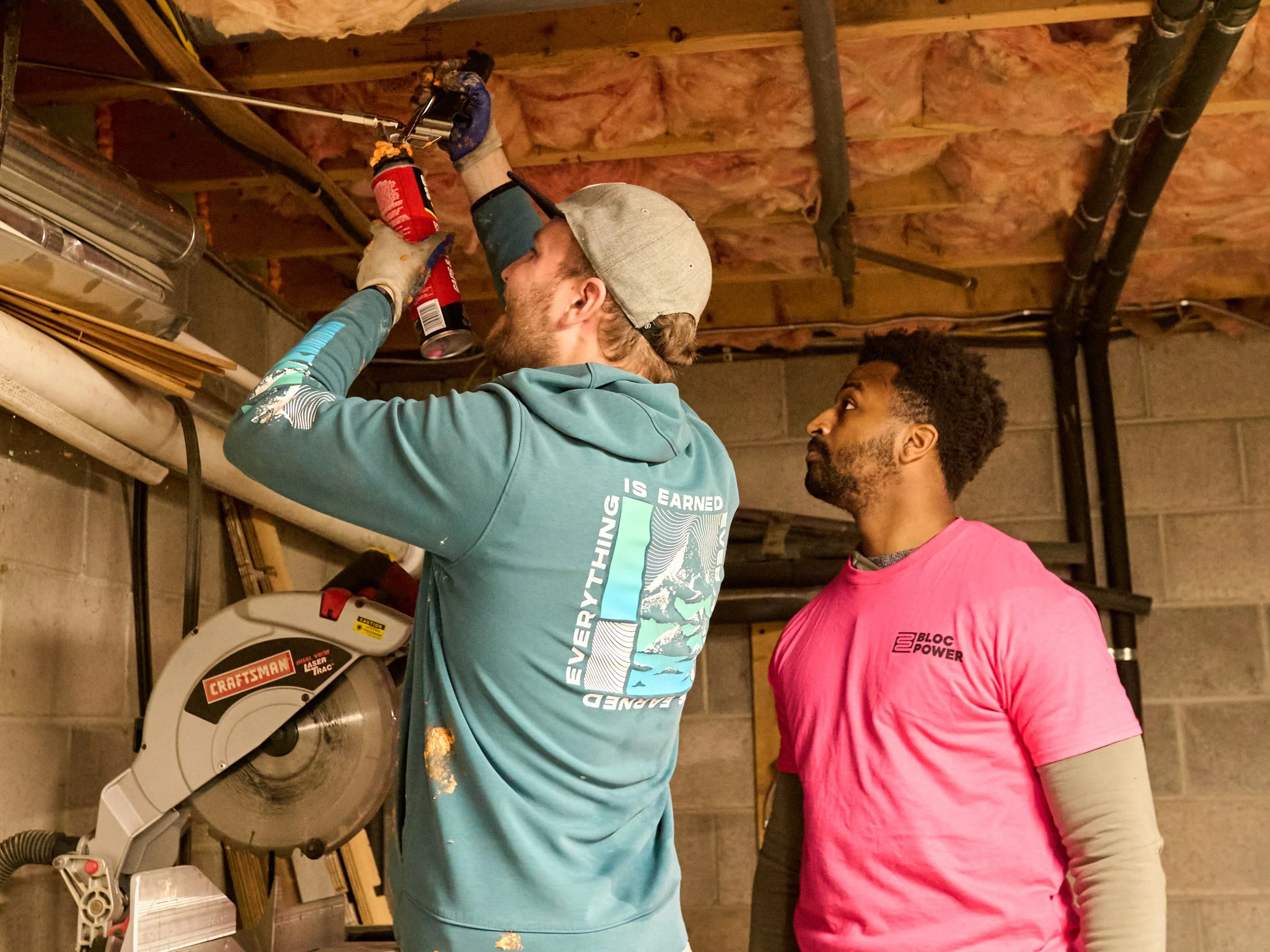 Man installing rim joist spray foam insulation in a basement.