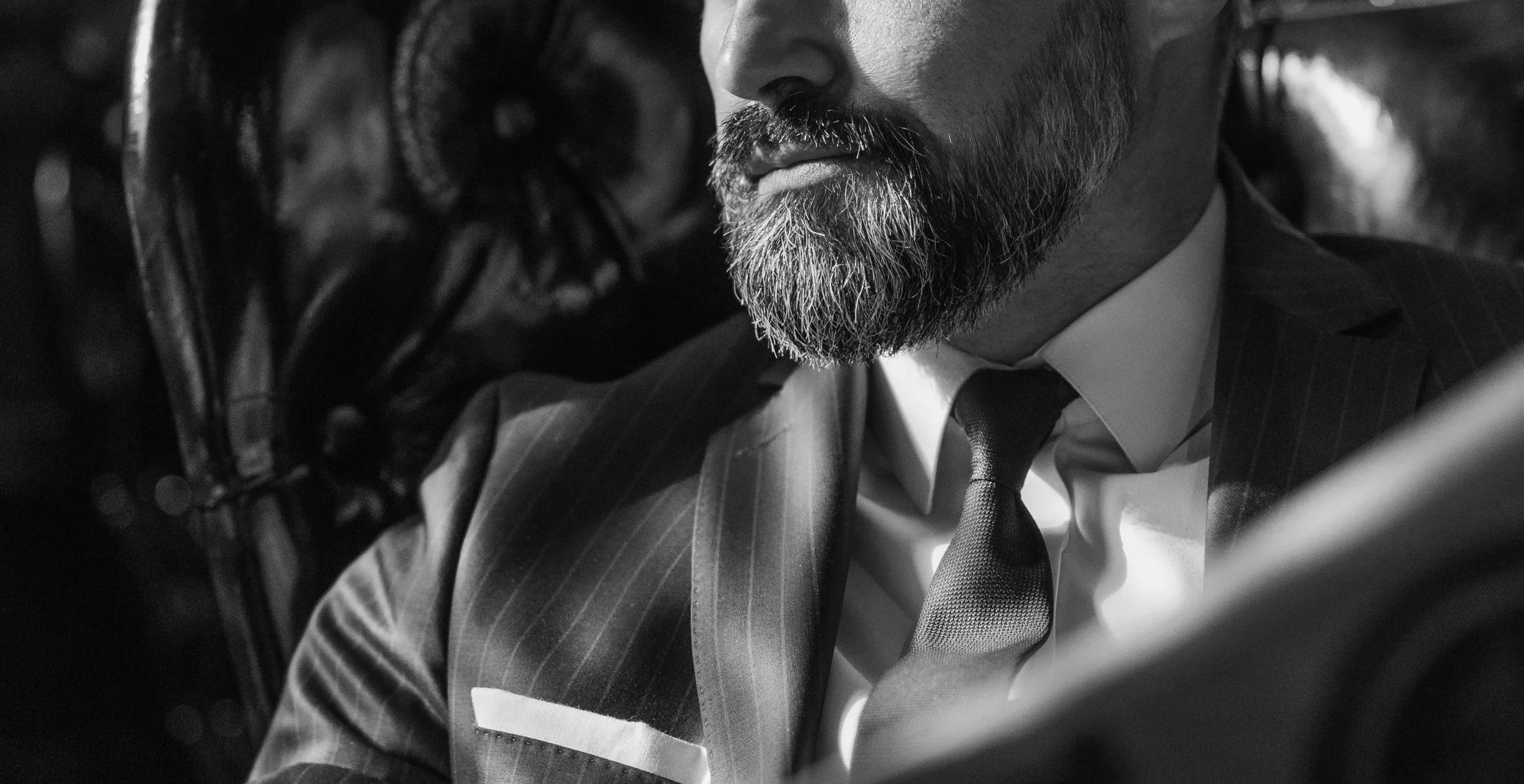 Close up of a man in a suit with a beard, looking away