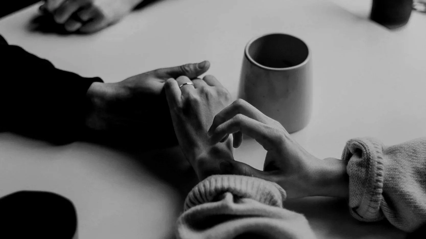 a couple holding hands over a table with a coffee