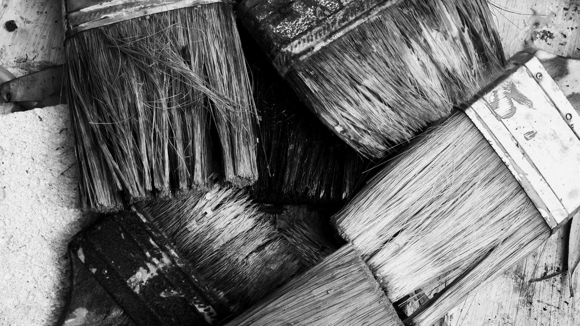 A close up of 5 used large paint brushes