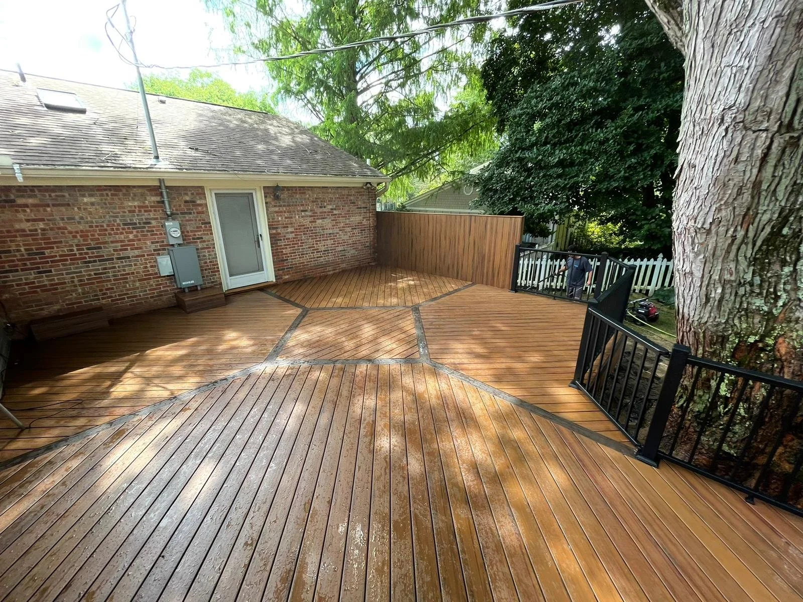 Custom hexagon composite deck with black aluminum railings built around a tree