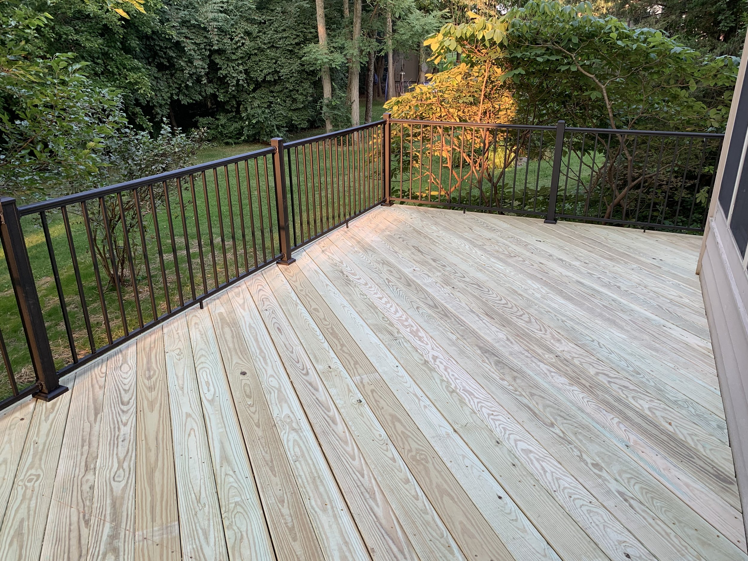 Pressure treated deck running diagnol with black railing.