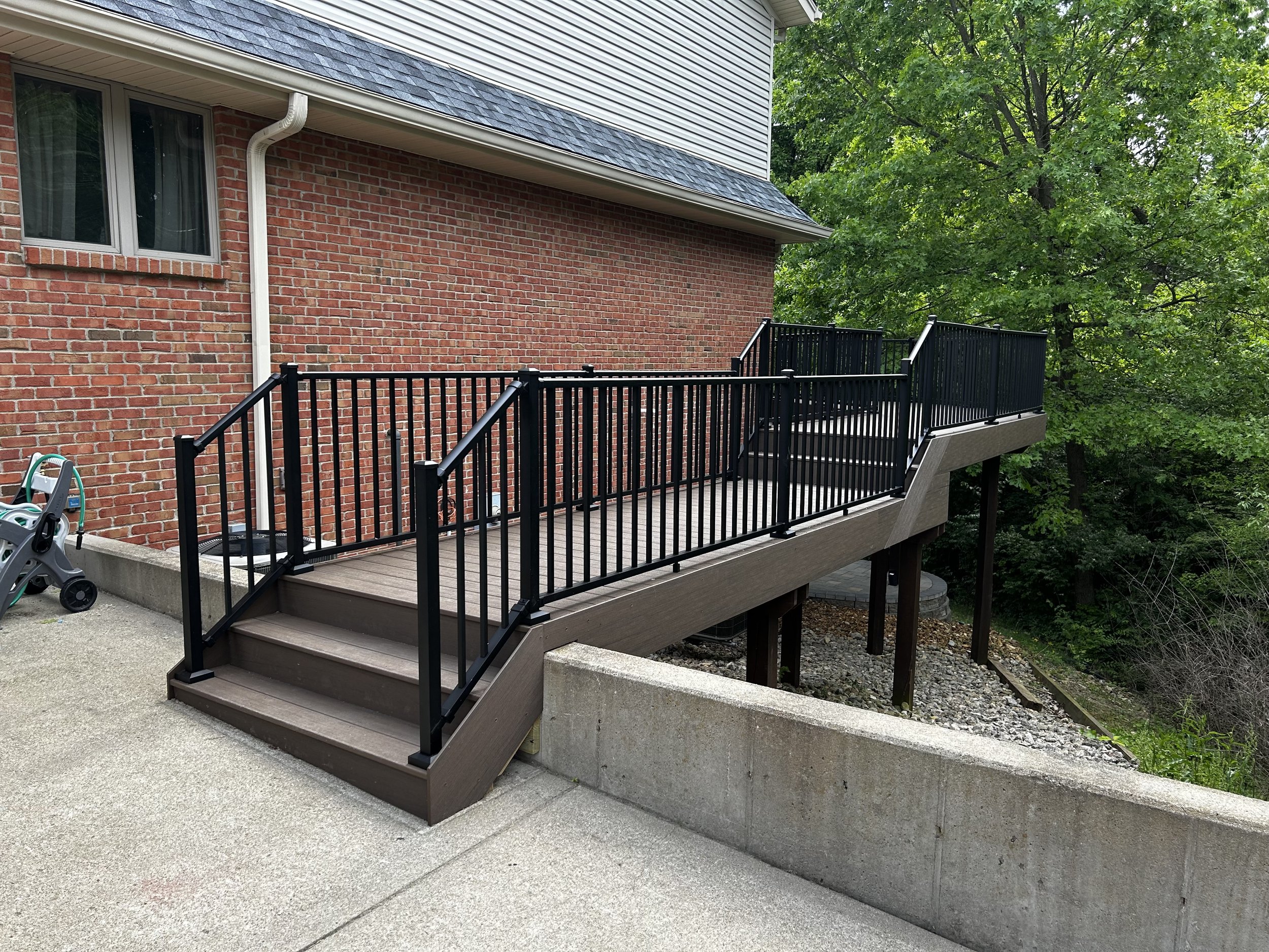 Elevated composite deck with black aluminum railings attached to a brick home