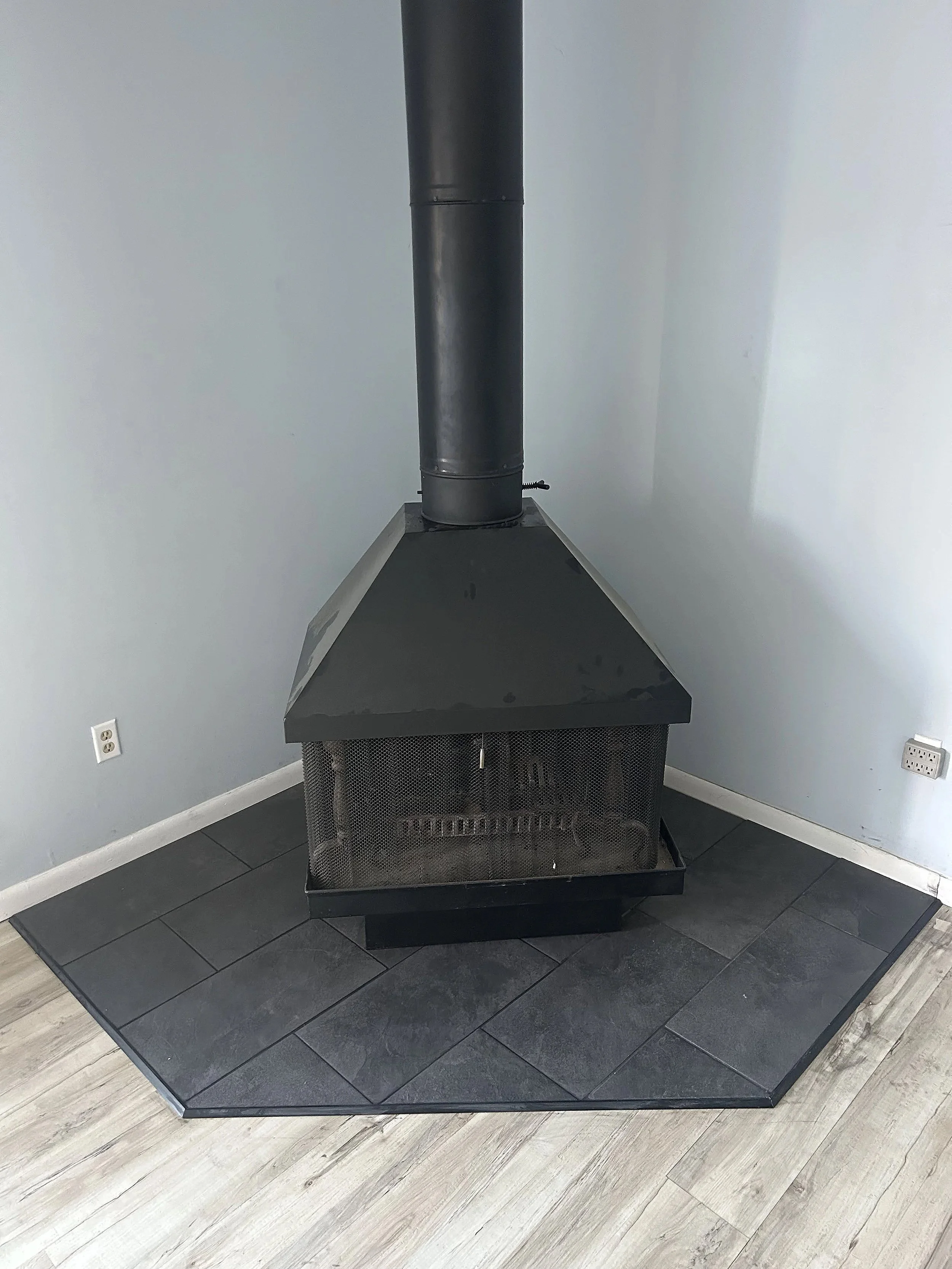 Stove on porcelain tile in the corner, surrounded by LVP flooring.