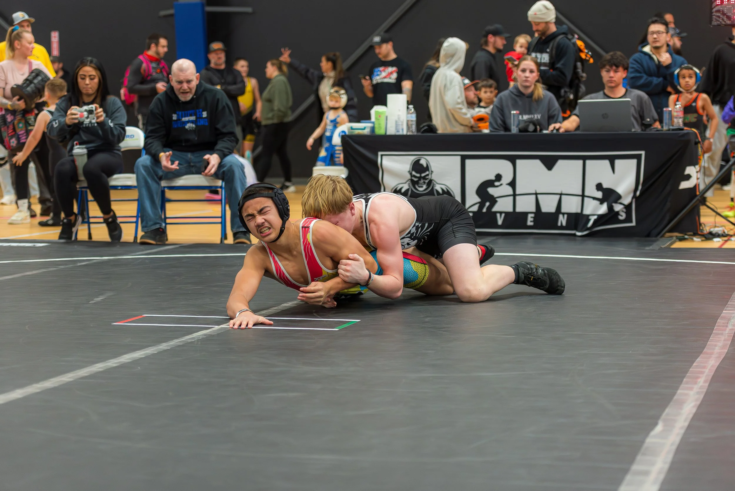 Youth wrestlers competing in a tournament match, highlighting how learning through loss and competition is part of healthy development in youth sports.