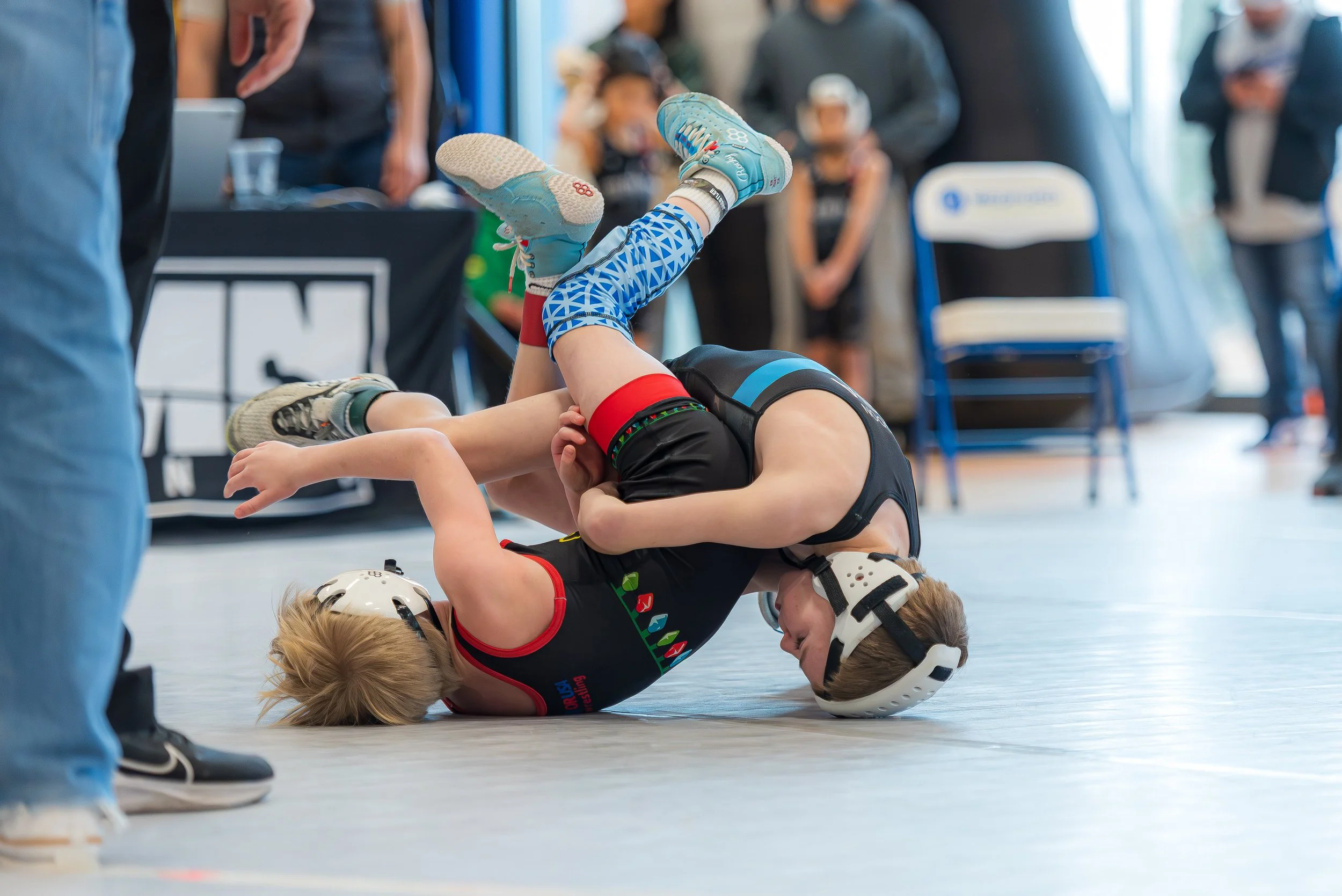 Wrestling coach talking with a young athlete after a match, emphasizing emotional support, reflection, and long-term athlete development.