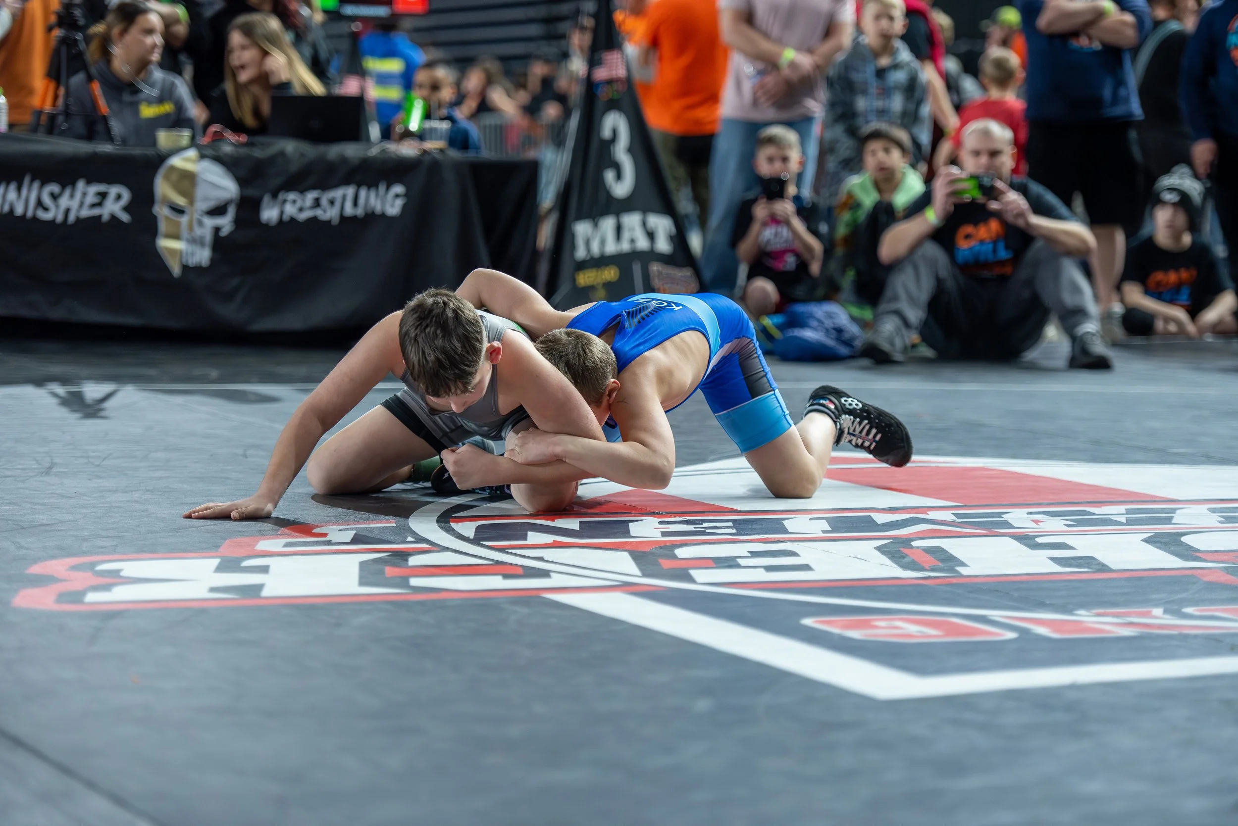 Youth wrestlers competing in tournament match representing long-term athlete development, discipline, and consistent summer training