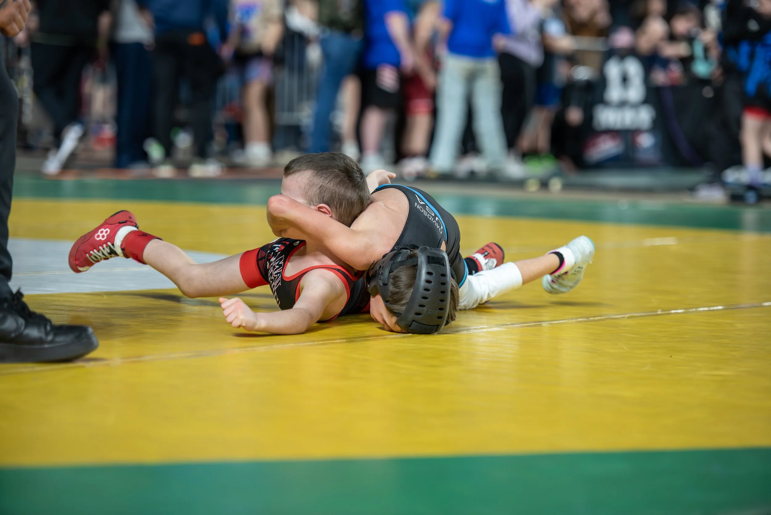 Young wrestlers competing during youth wrestling match showing discipline development, consistency, and long-term athlete growth