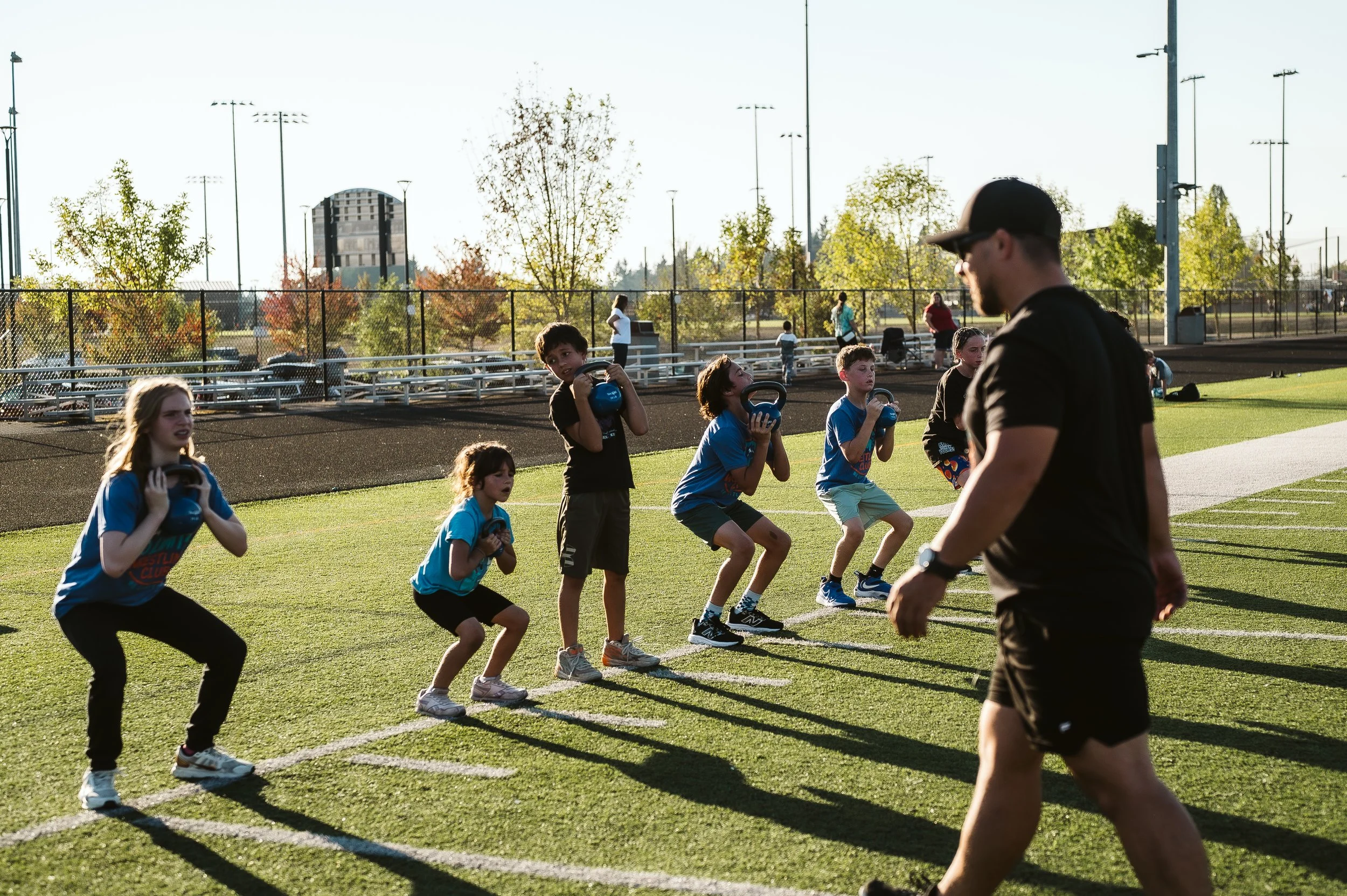 Youth athletes performing summer strength and conditioning training with coach supervision during offseason athletic development