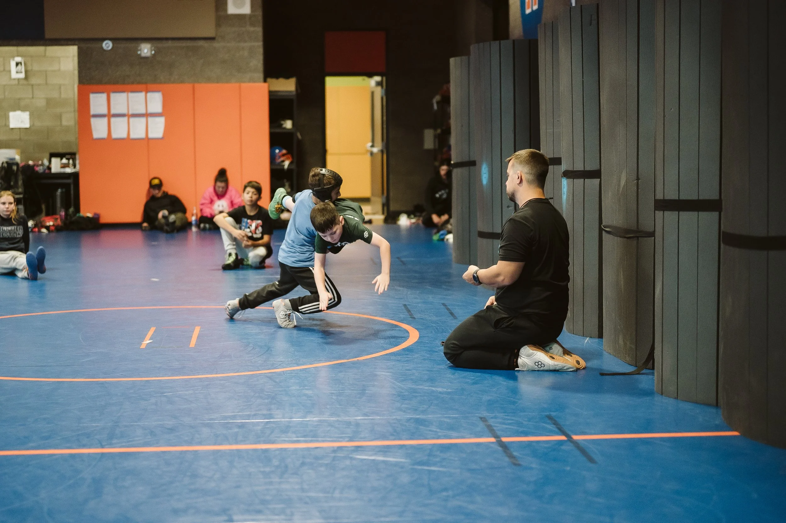 Youth wrestling practice with coach leading structured training and athlete development during offseason