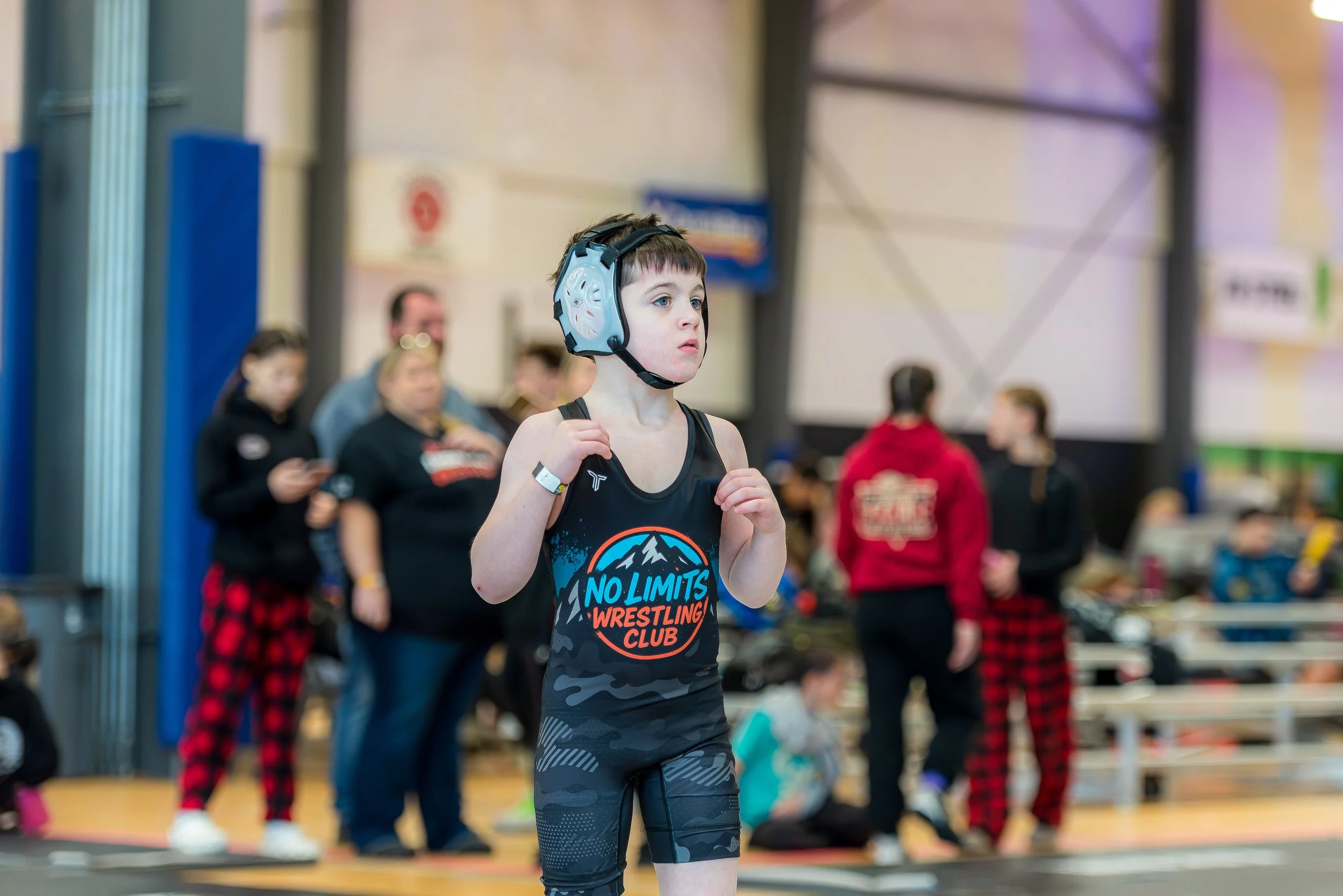 Child wrestler participating in a youth wrestling tournament, showing the early stages of athletic growth and skill development over time.